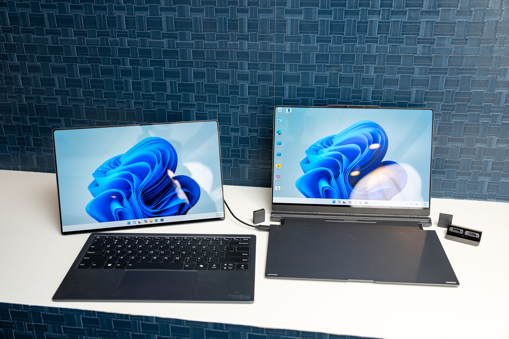 A ThinkBook Modular AI PC Concept laptop with its keyboard removed and set beside its second screen, which is propped up on a kickstand and connected via USB-C. To its side are some modular ports set to the side.