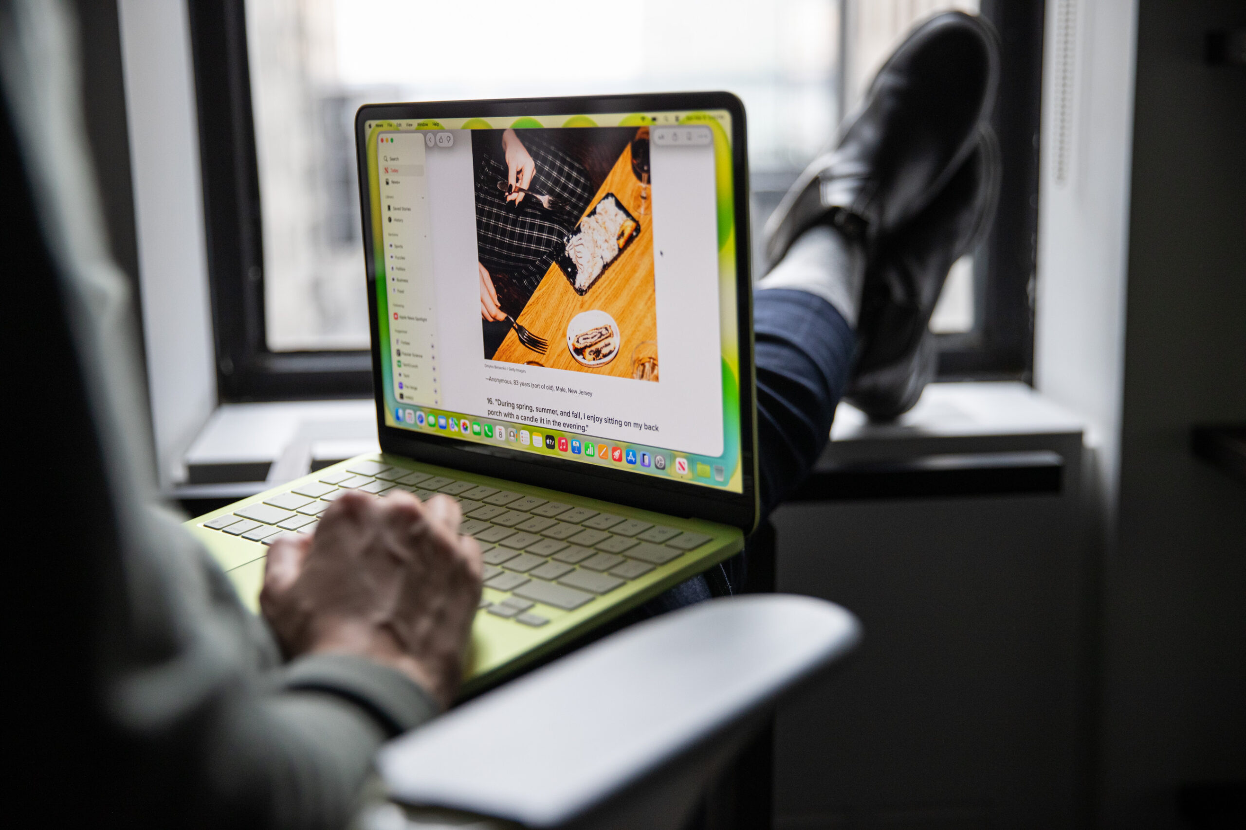 A photo of a person using a laptop with their feet propped up on a window.