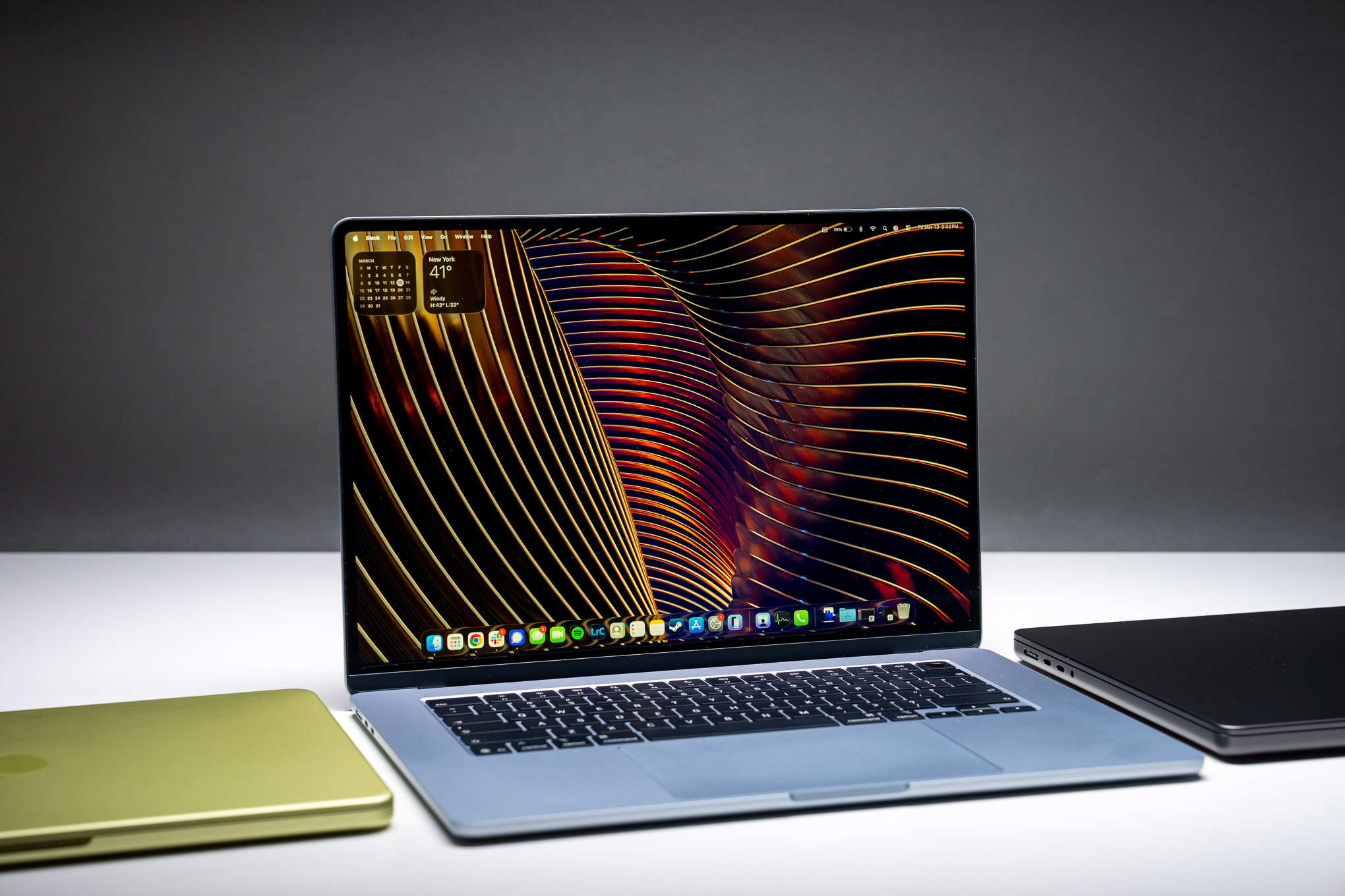 A 15-inch MacBook Air M5 open and sitting between a MacBook Neo and MacBook Pro.