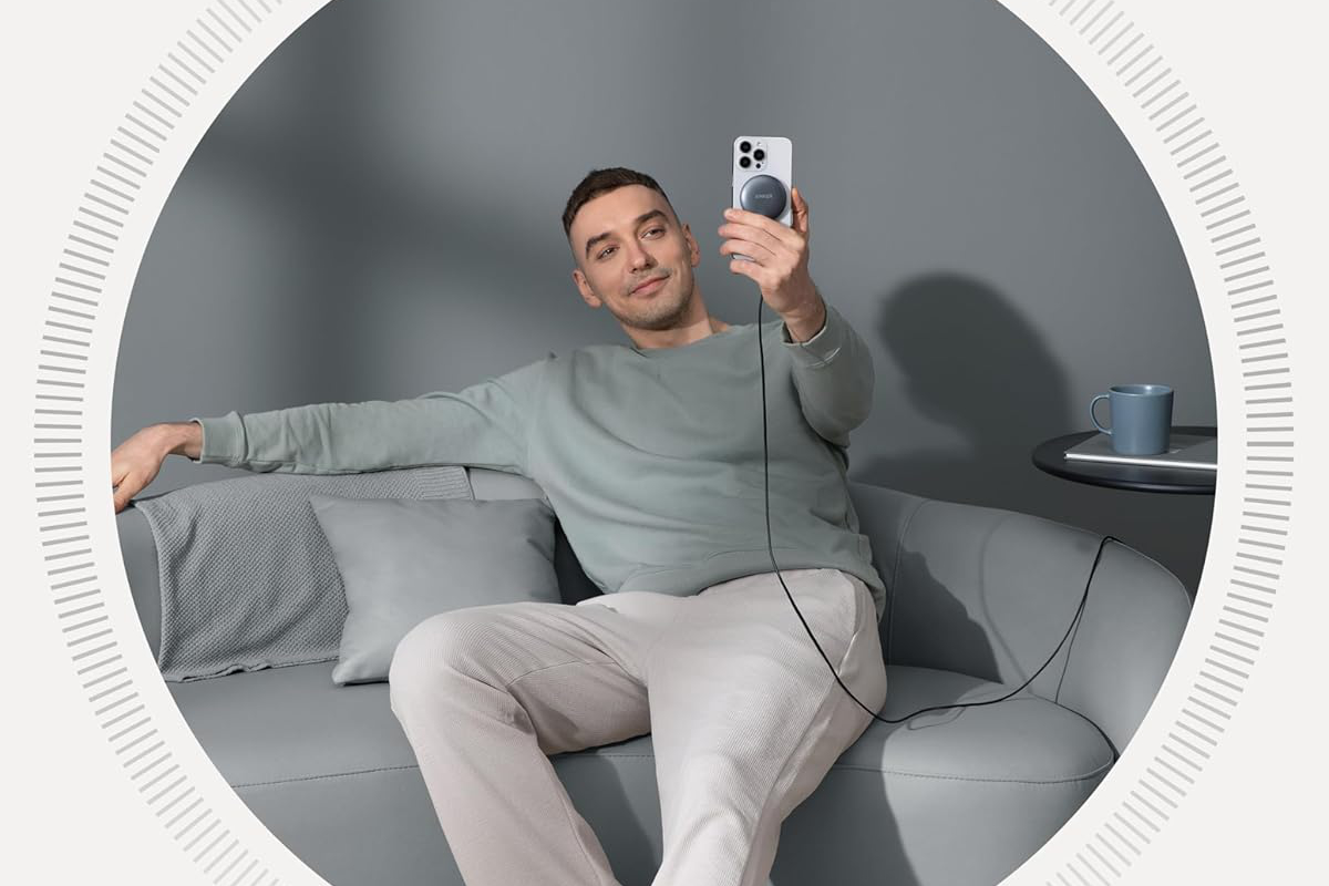 A person holds up their phone while it’s magnetically attached to Anker’s MagGo 15W Qi2 wireless charging pad.