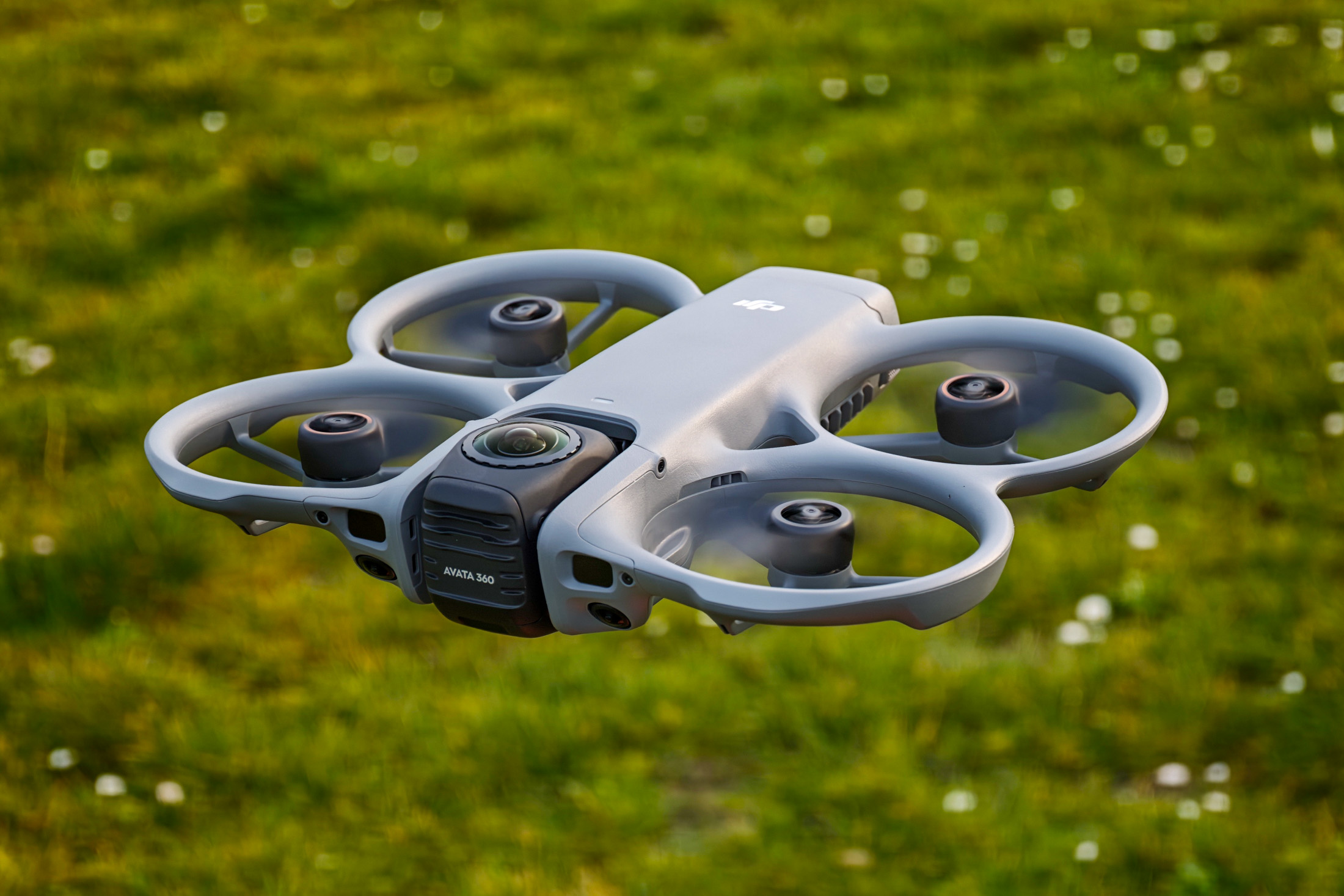 Photo of the DJI Avata 360 hovering above grass