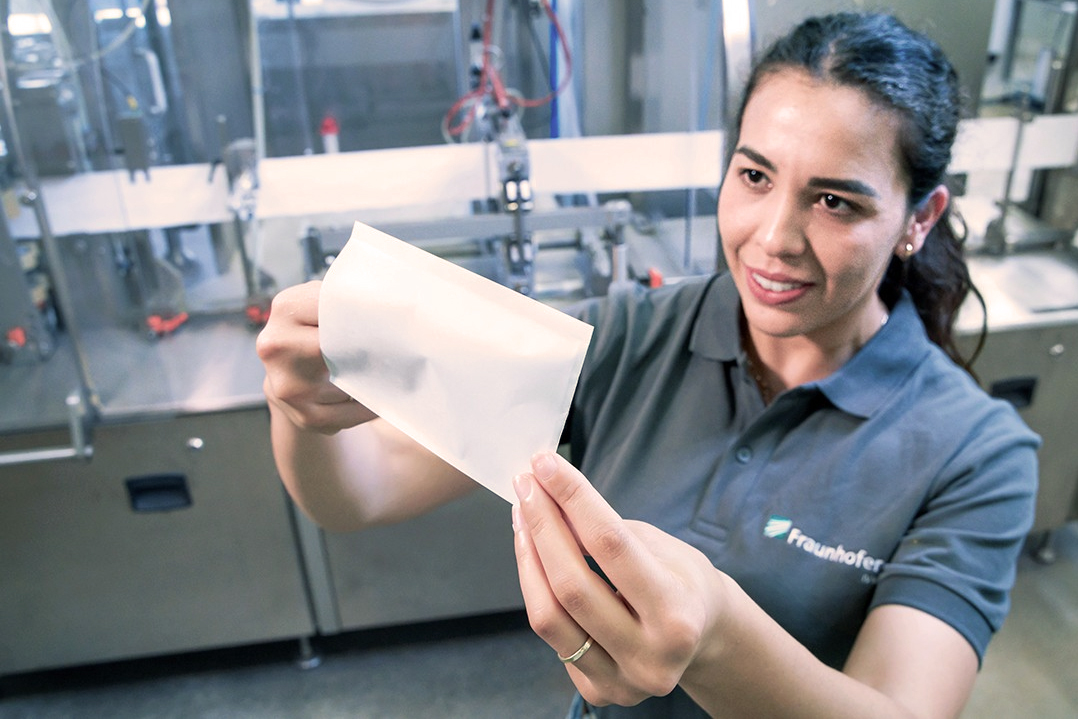 A person holds a small paper bag that has been sealed using a new laser system.