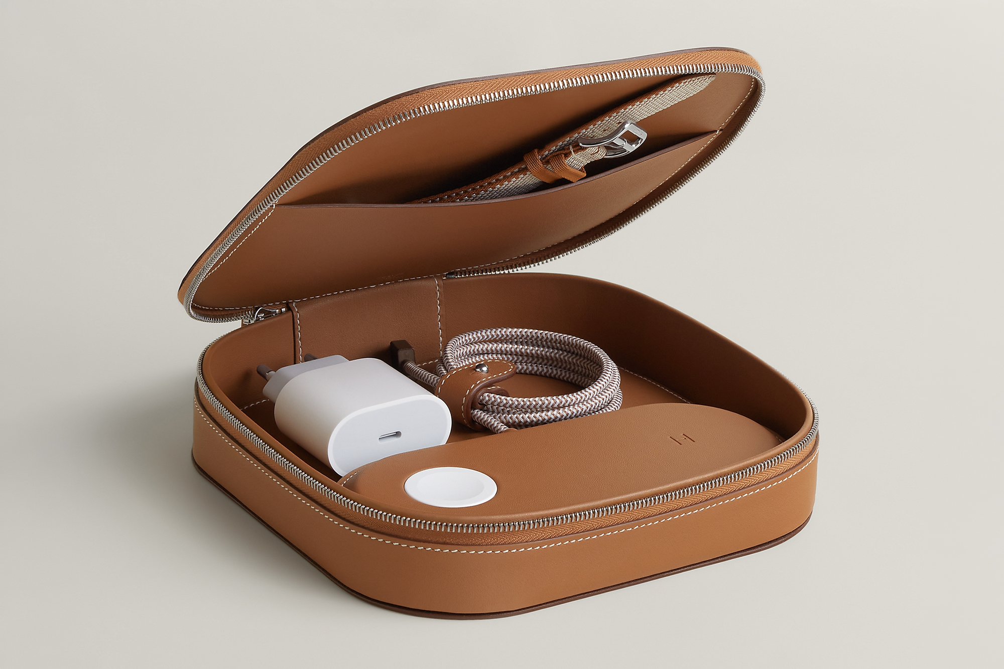 The Hermès Paddock Duo charger and Grand Paddock case unzipped with extra accessories inside.