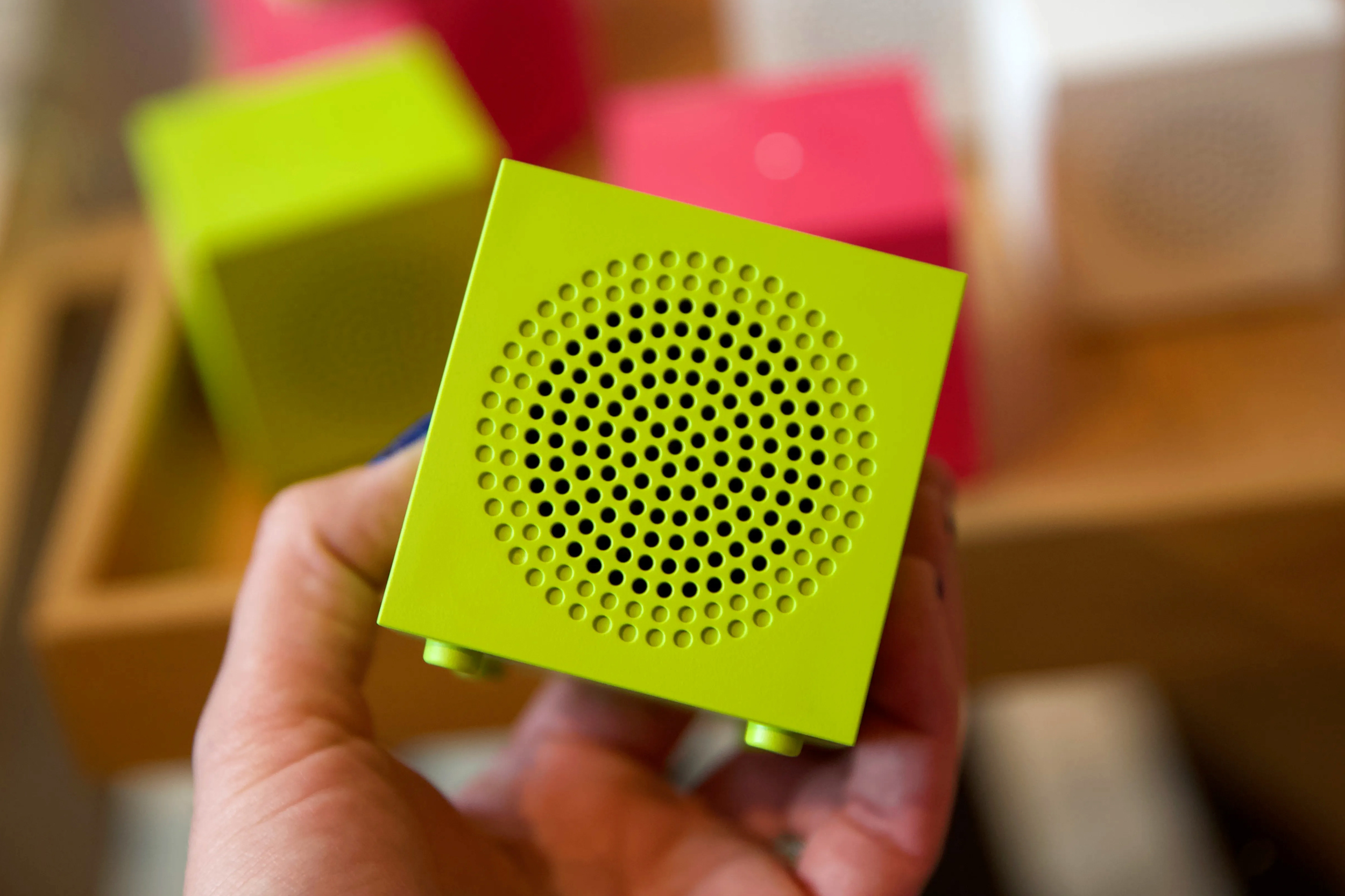 A person holds the green version of Ikea’s Kallsup Bluetooth speaker.