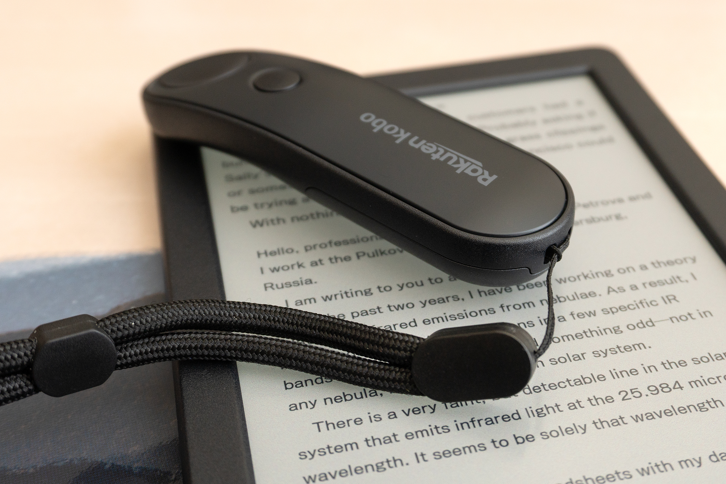 The Kobo Remote with a lanyard attached sitting on a Kobo e-reader. The Kobo Remote with a lanyard attached sitting on a Kobo e-reader.