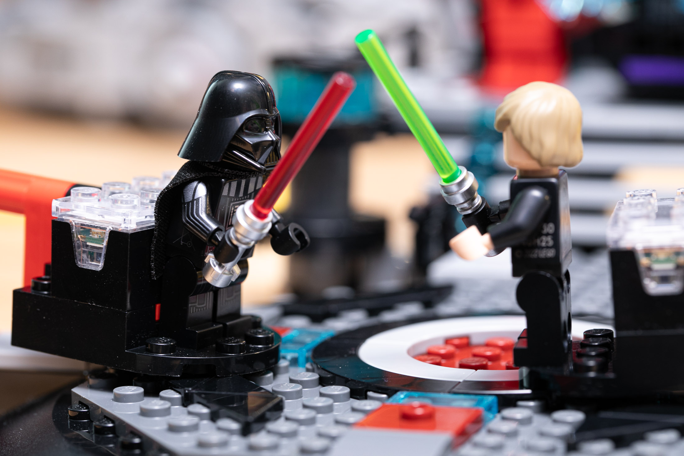 Lego Darth Vader and Luke Skywalker minifigures duel with their lightsabers, attached to platforms with the Lego Smart Brick