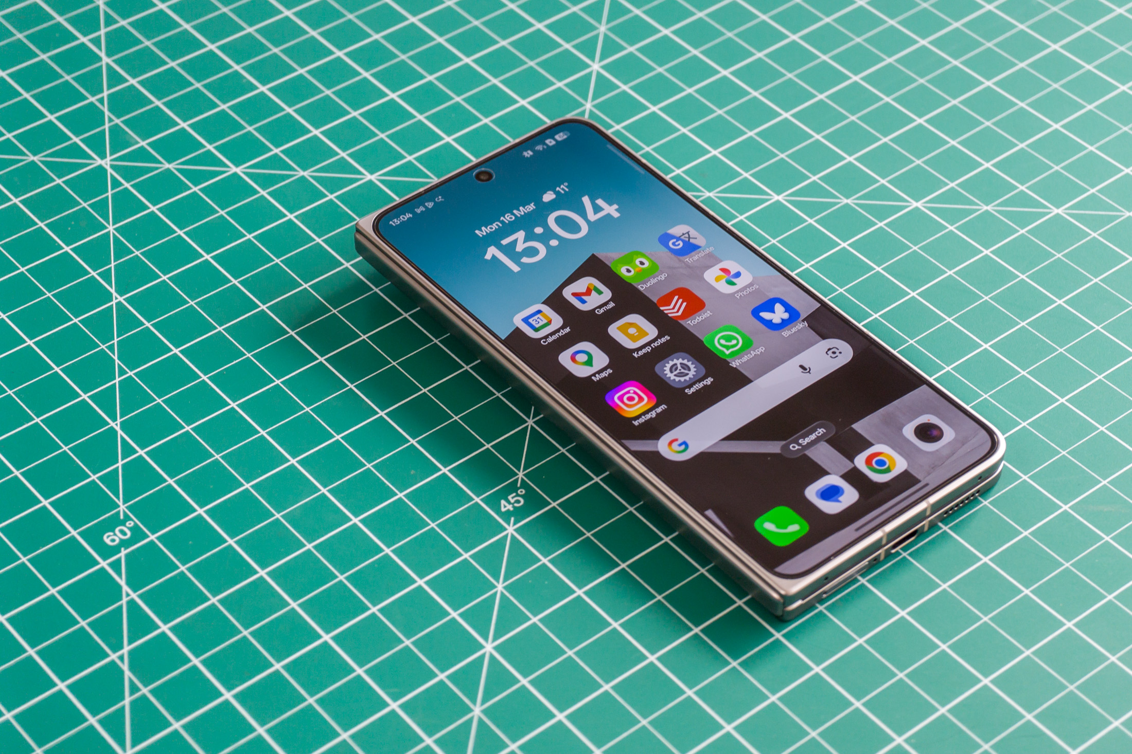 Photo of Oppo Find N6 on a green work mat from above at an angle, closed with the front screen on