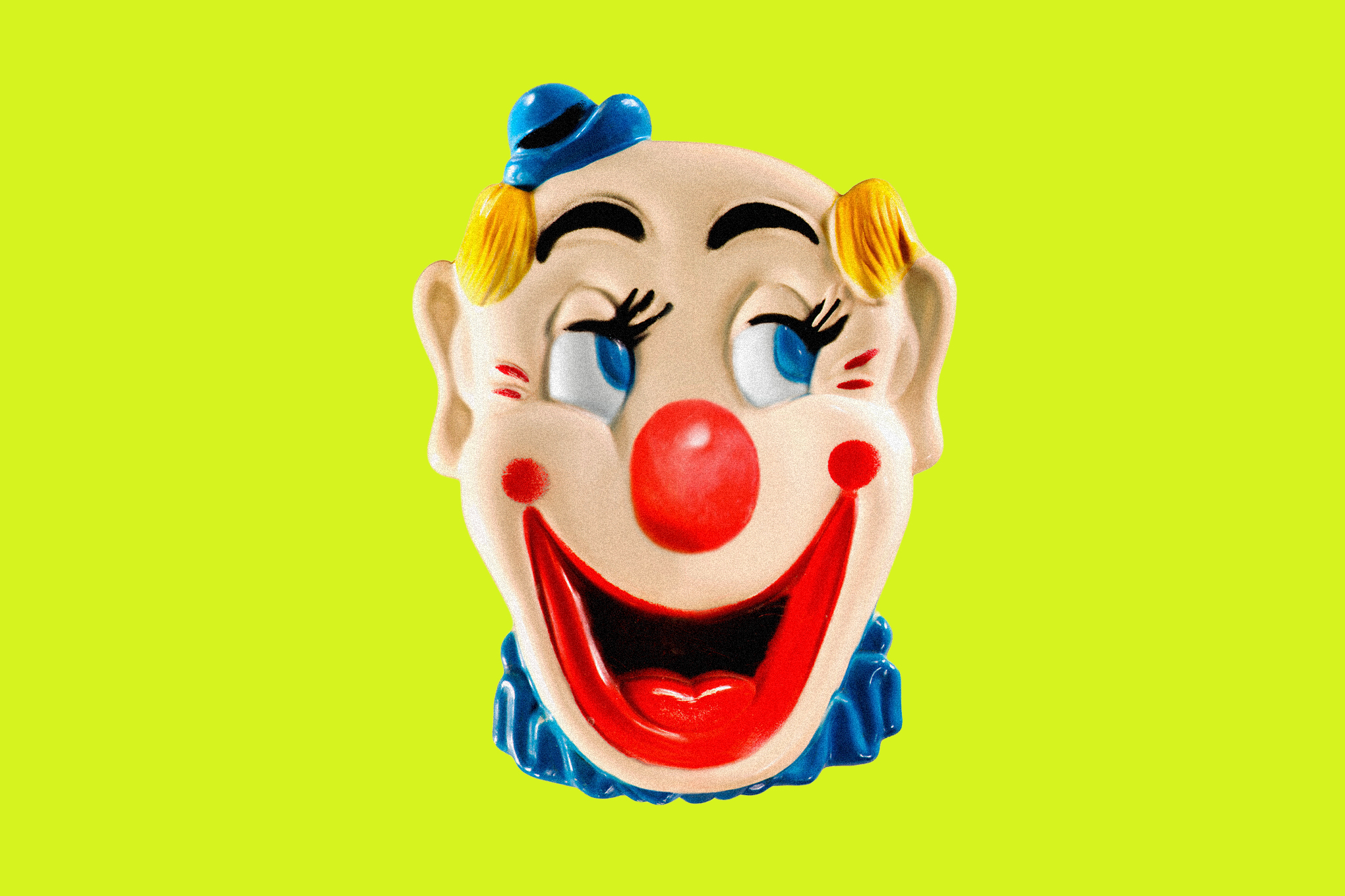 A clown face with s huge smile on a lime green background