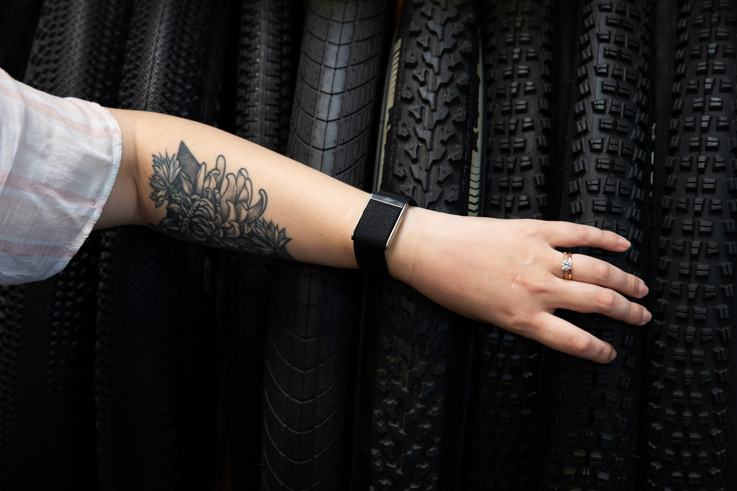 Person with tattooed forearm resting arm with a Whoop MG band on a set of tires.