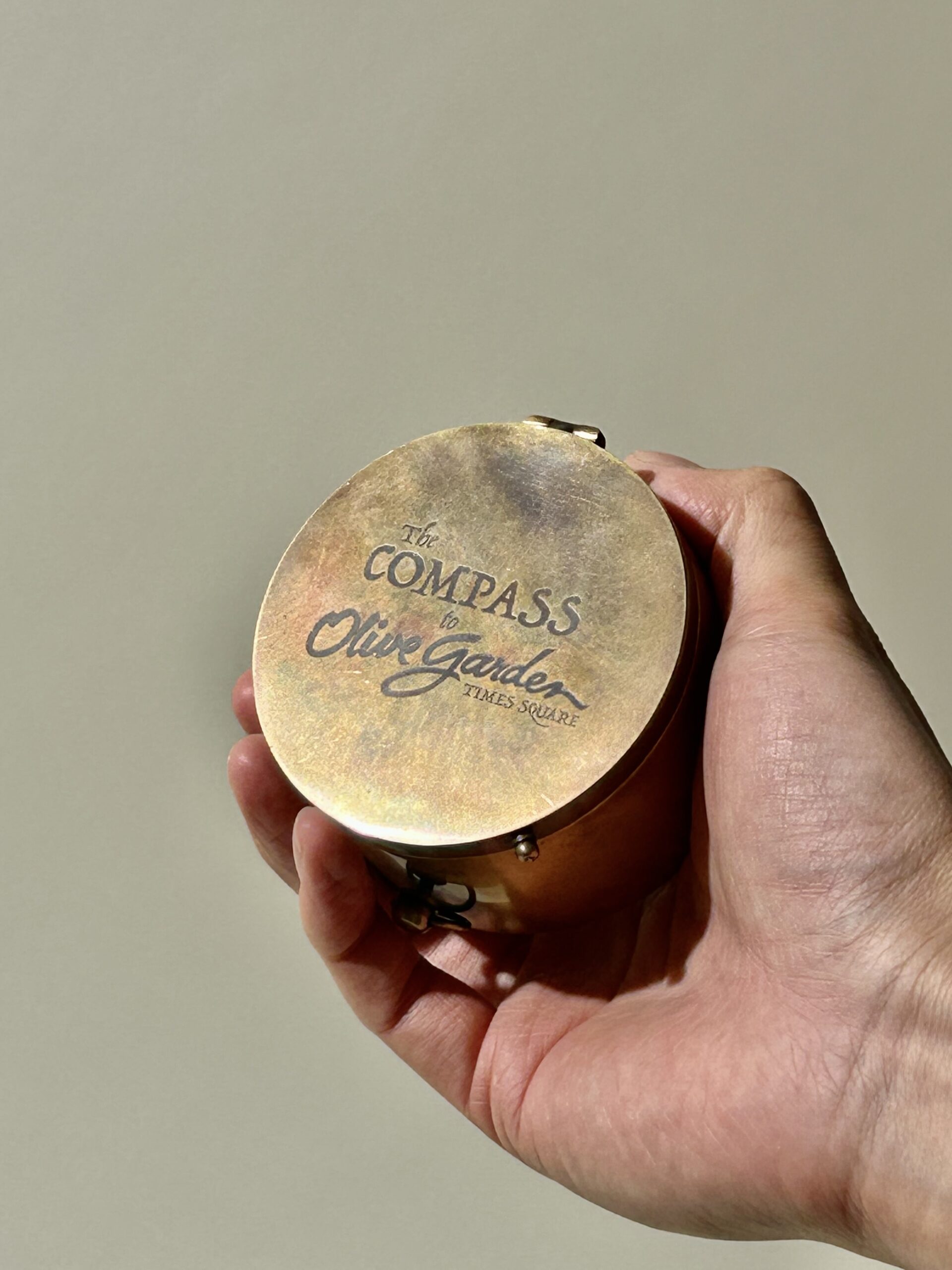 A bronze cylindrical compass that points to the Times Square Olive Garden