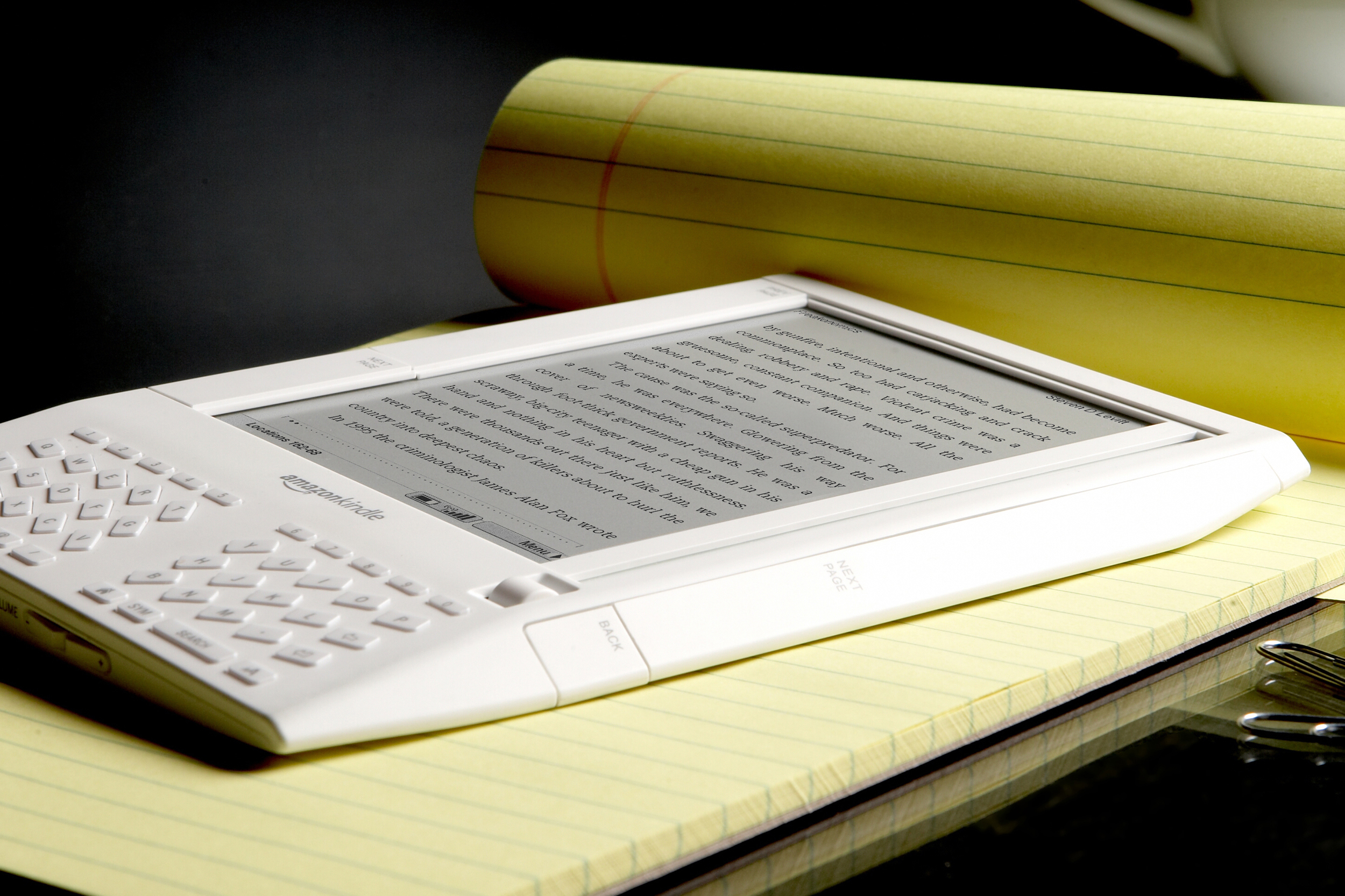 The 1st generation Amazon Kindle e-reader sitting on a legal pad.