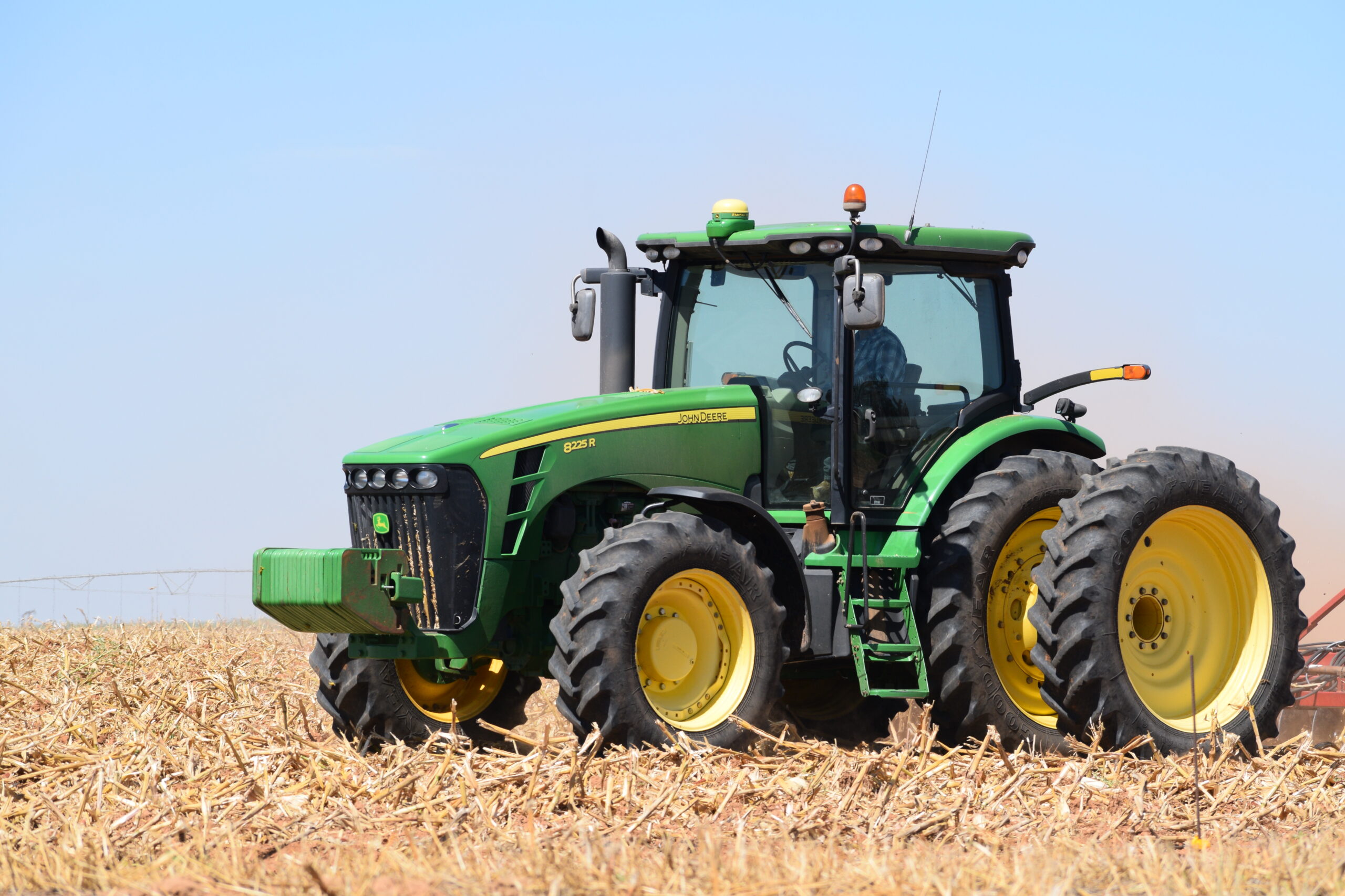 Farmer driving a John Deere 8225 R tractor on his farm near Rochester Texas.