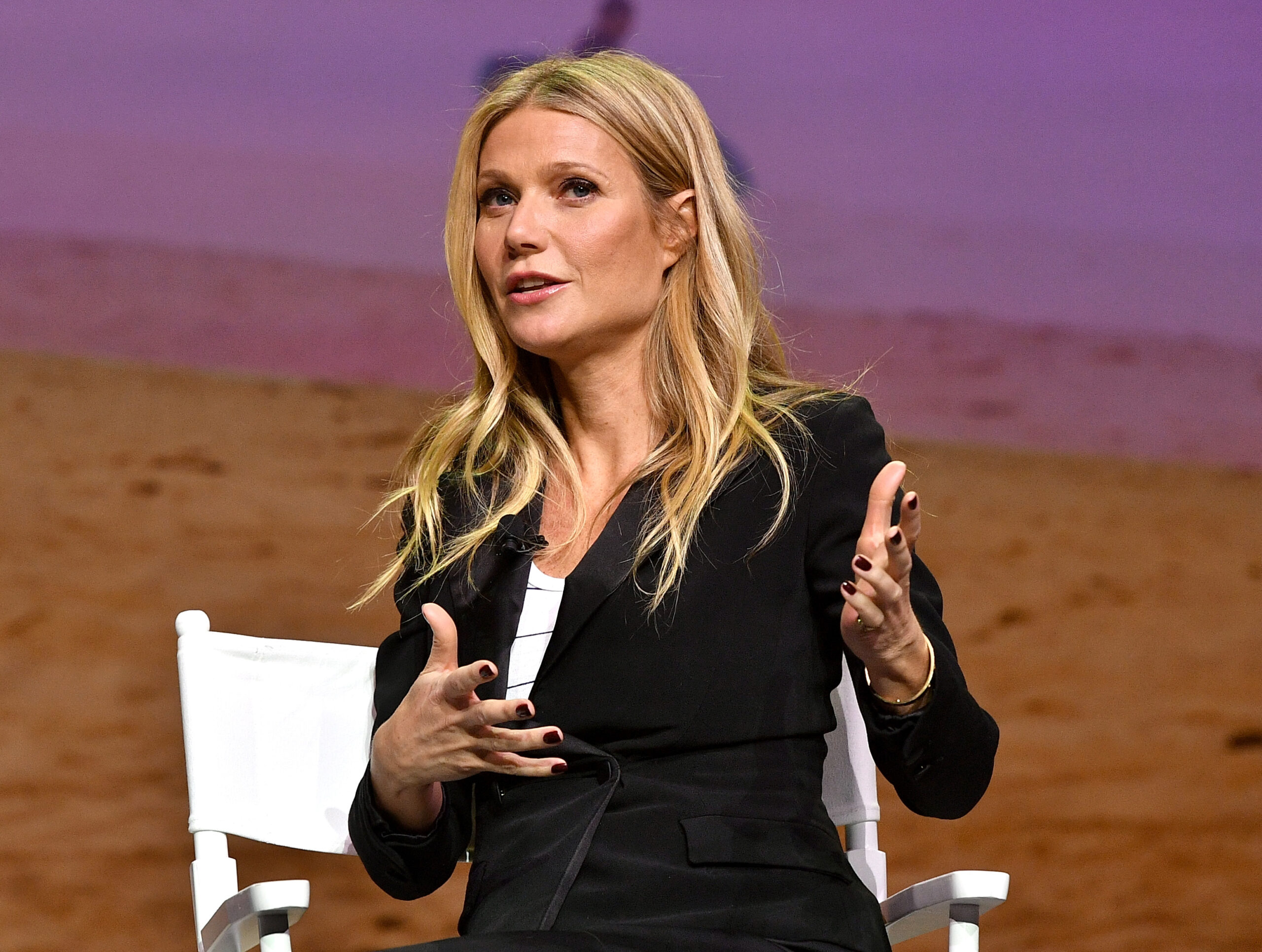 Gwyneth Paltrow sitting in a white chair while gesturing