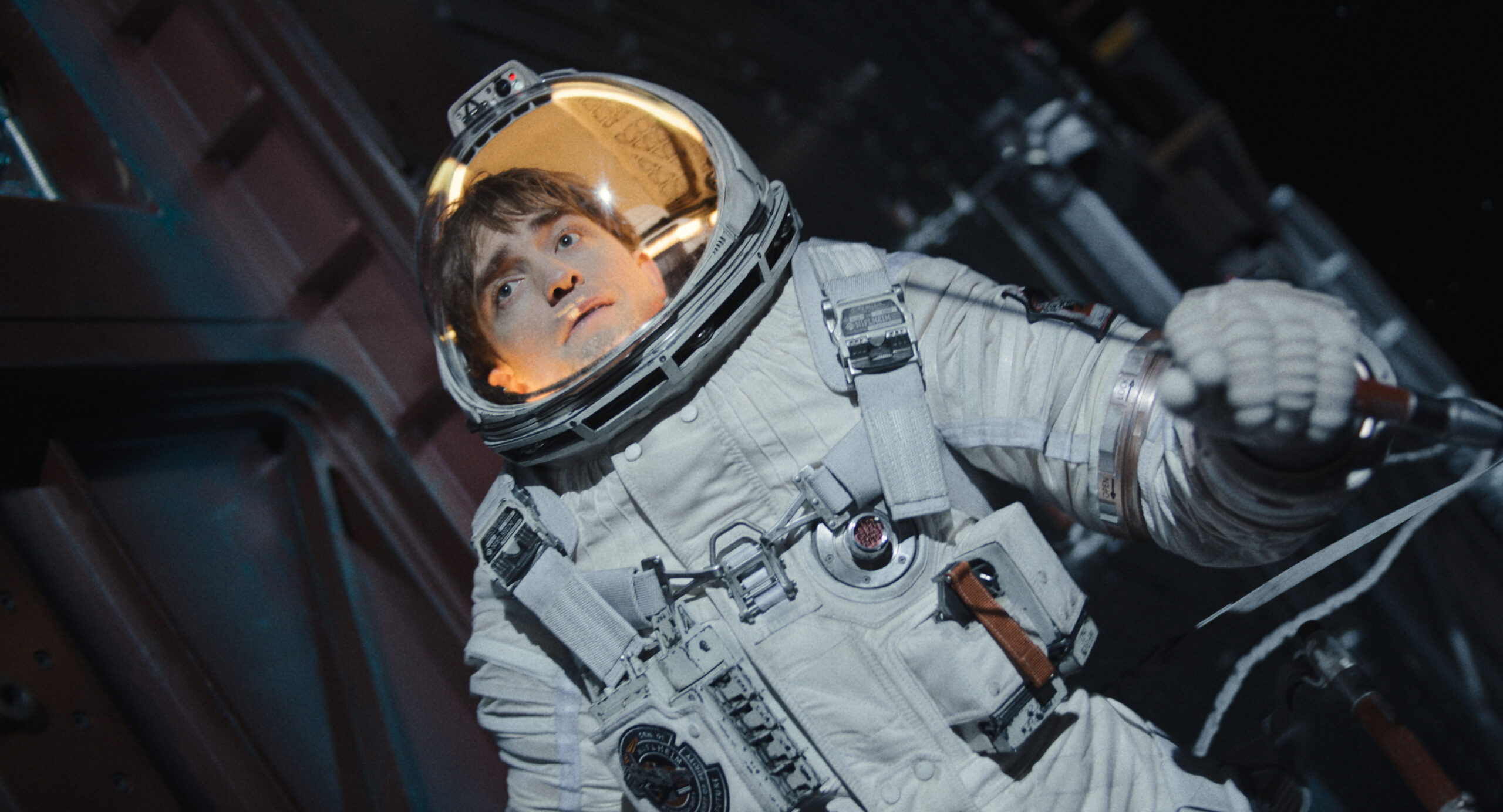 A man in a space suit floating in space while tethered to a ship.