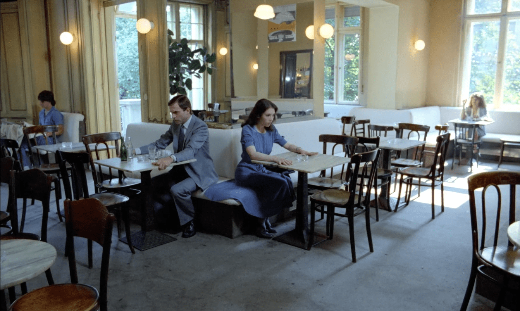 Sam Neill and Isabelle Adjani seated in a cafe facing away from each other in 1981’s Possession.