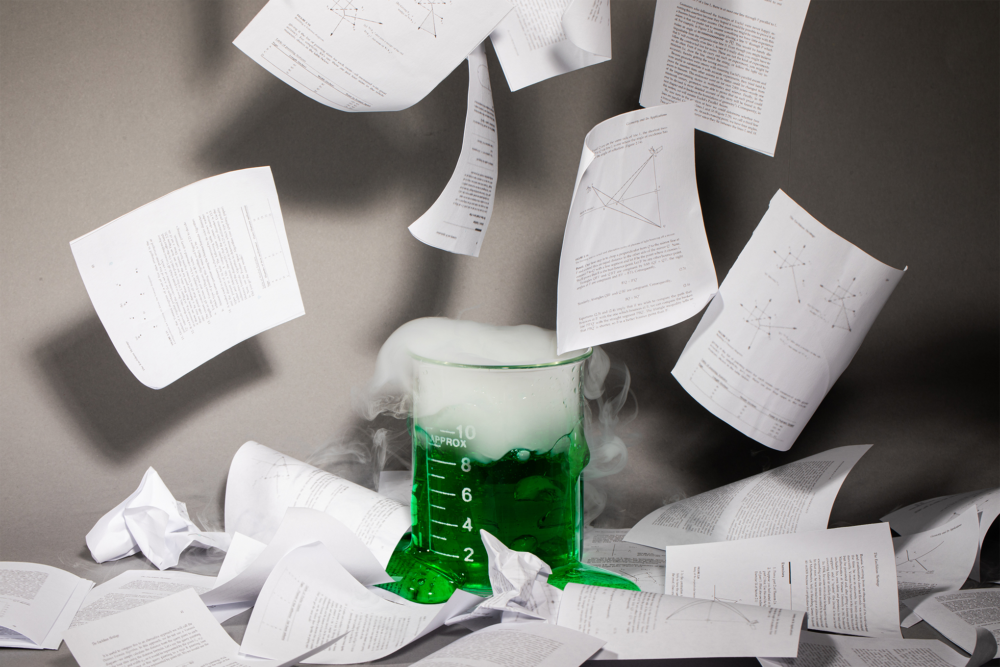 Beaker overflowing with green slime and smoke as research papers fly out of it.