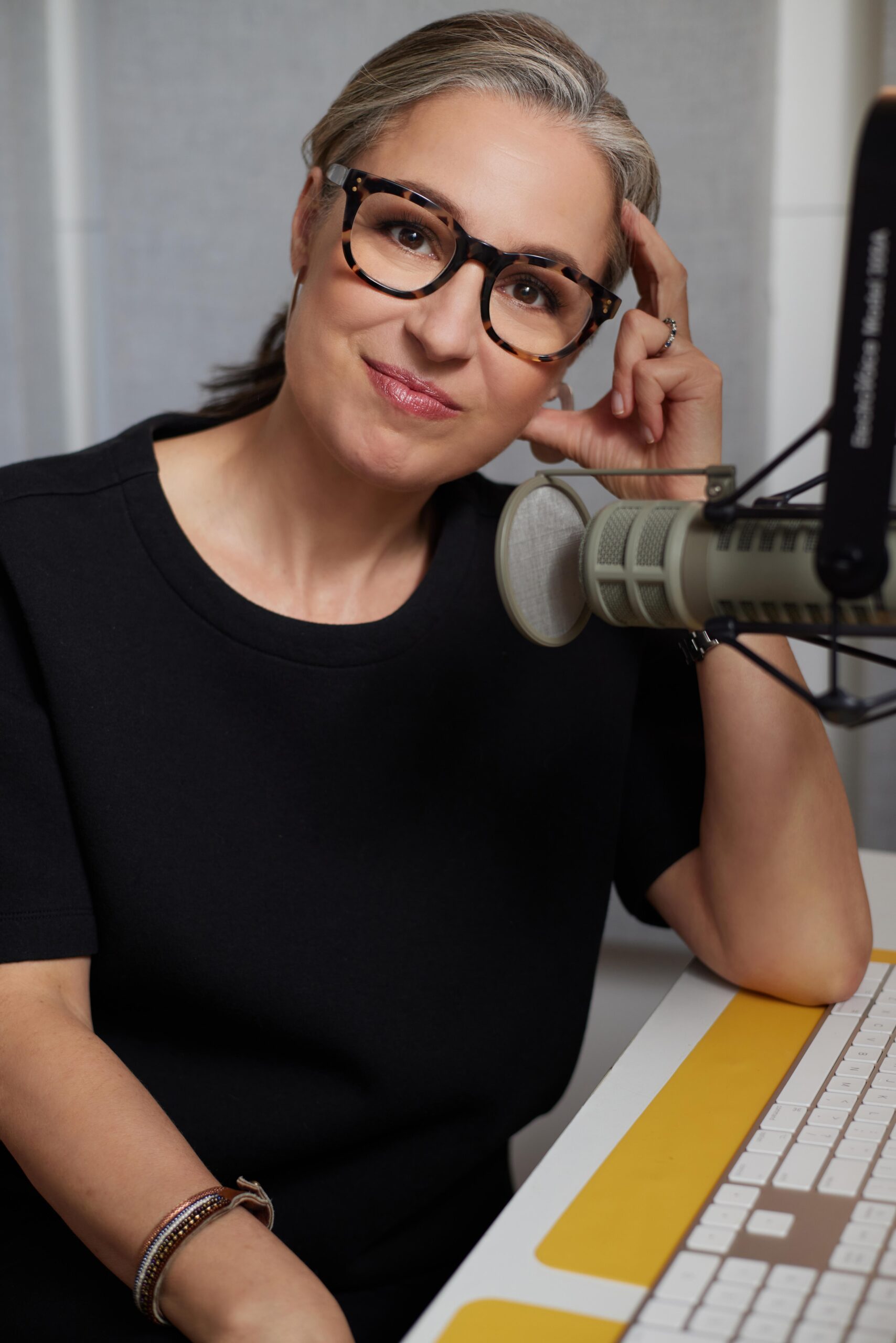 NPR’s Manoush Zomorodi siting at a desk with a microphone in front of her.