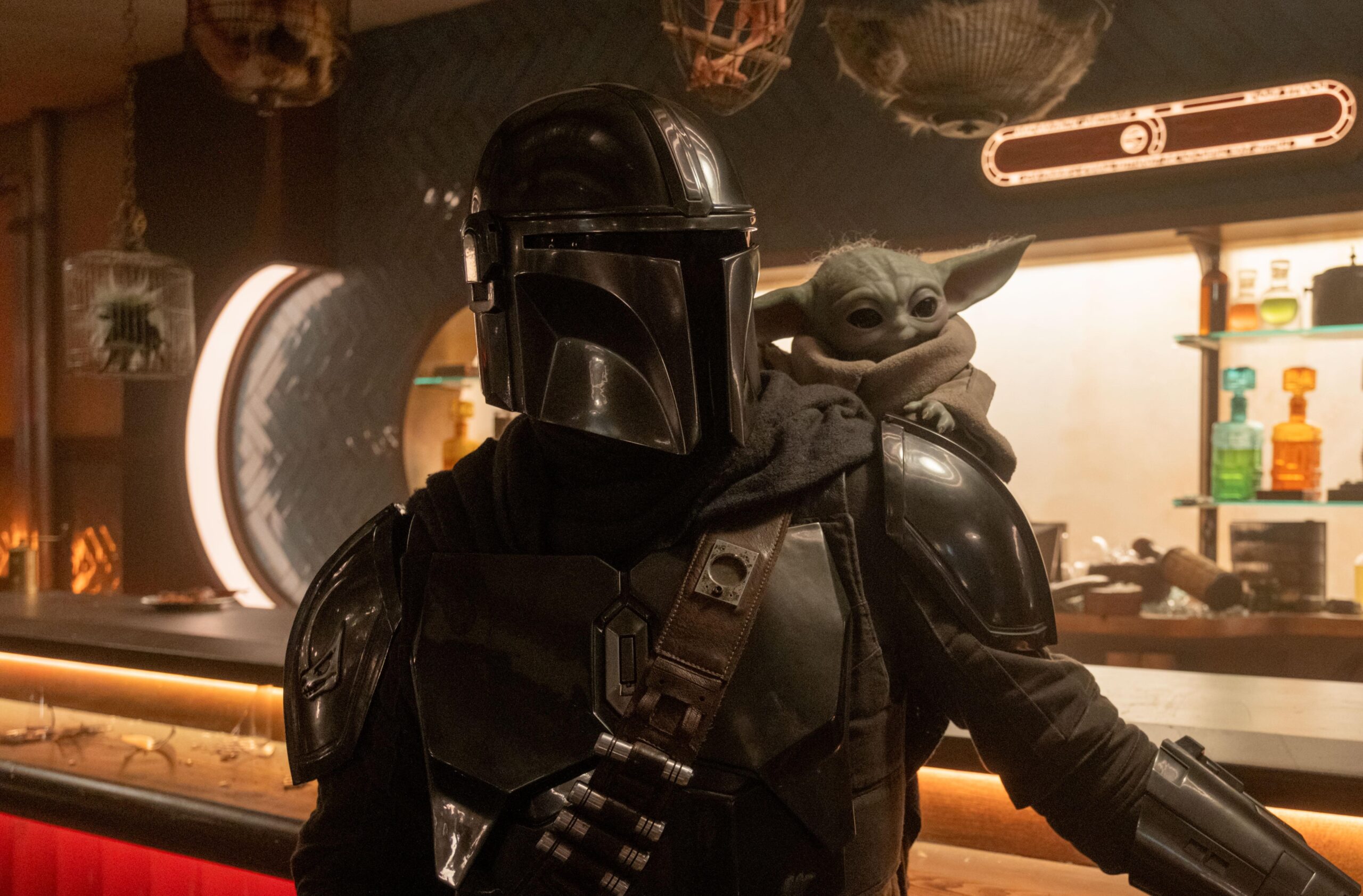 The Mandalorian and Grogu standing together in a cantina.
