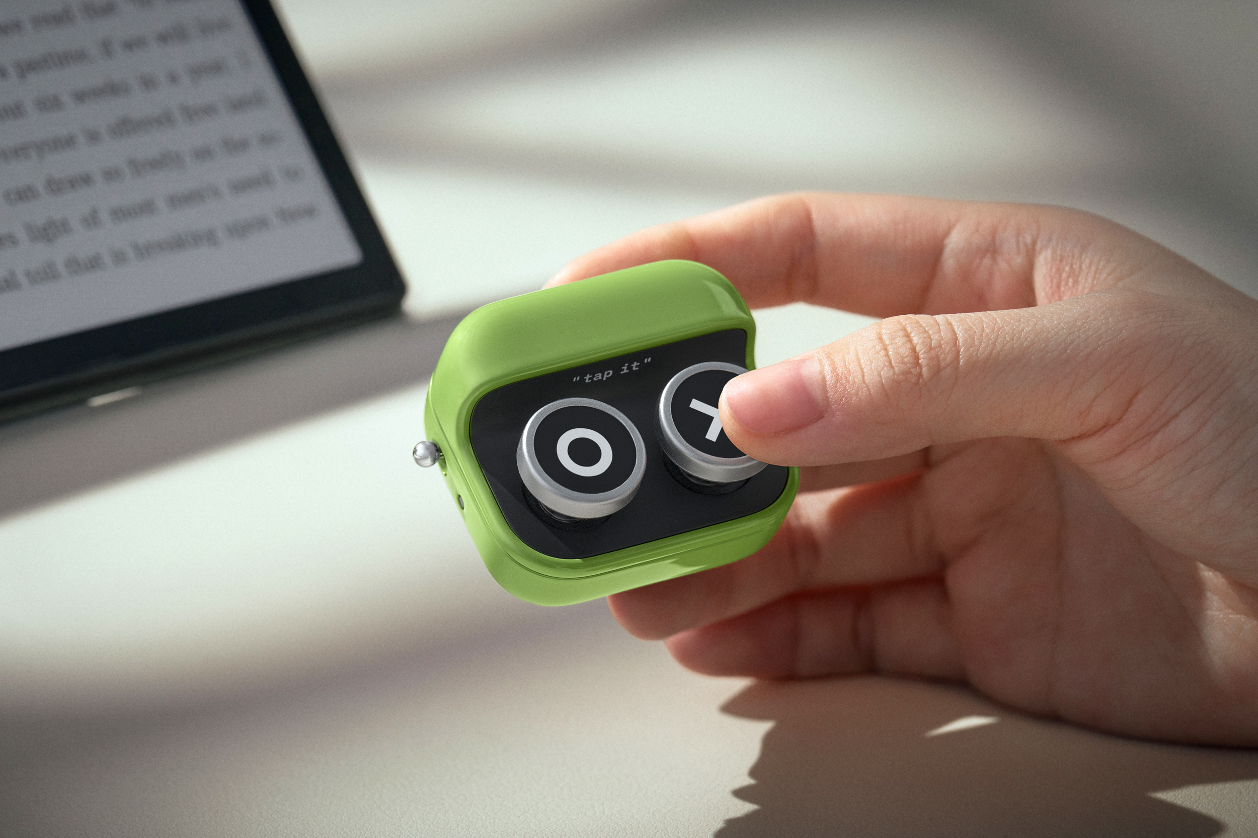 A person holds the Boox Tappy remote in one hand while pressing one of its buttons.