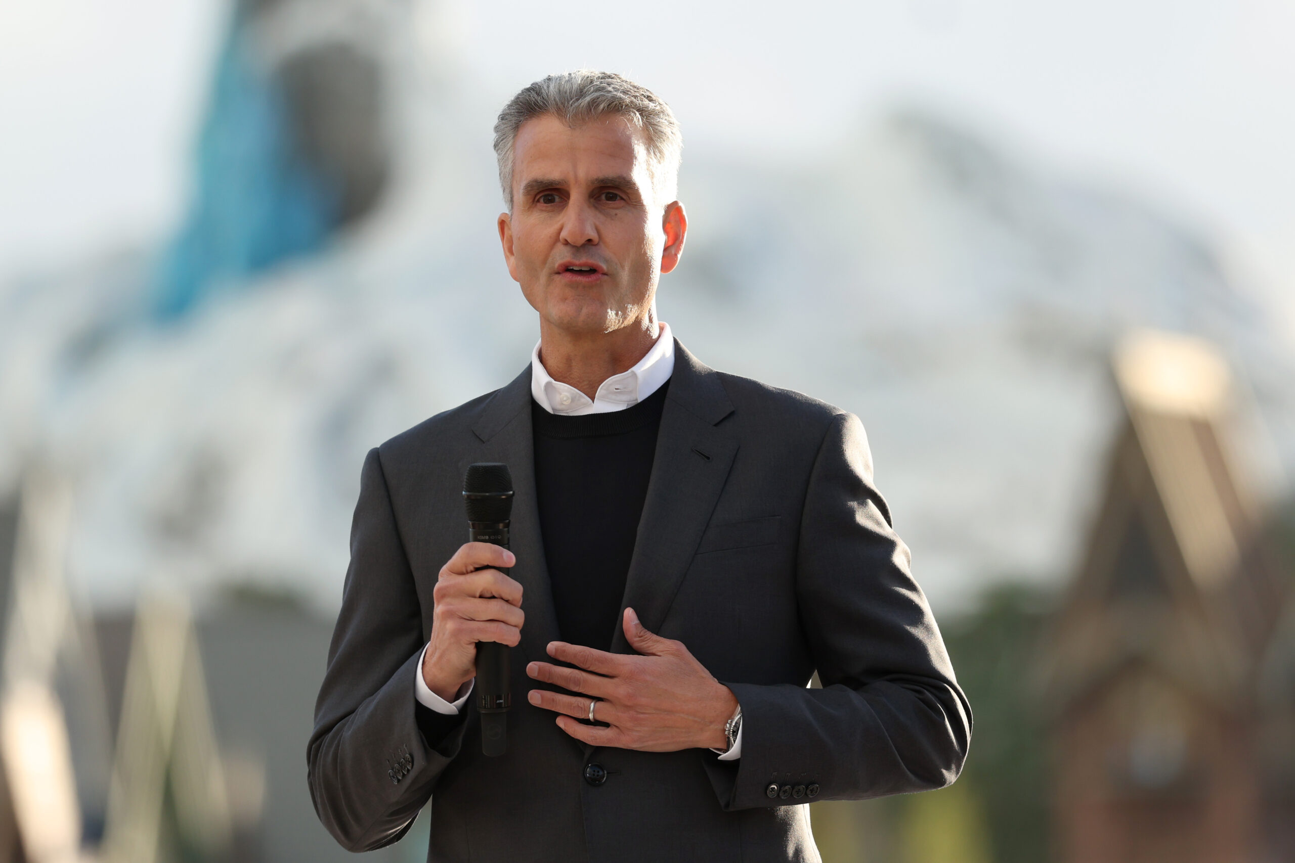Disney CEO Josh D’Amaro holding a microphone while speaking to a group of people.