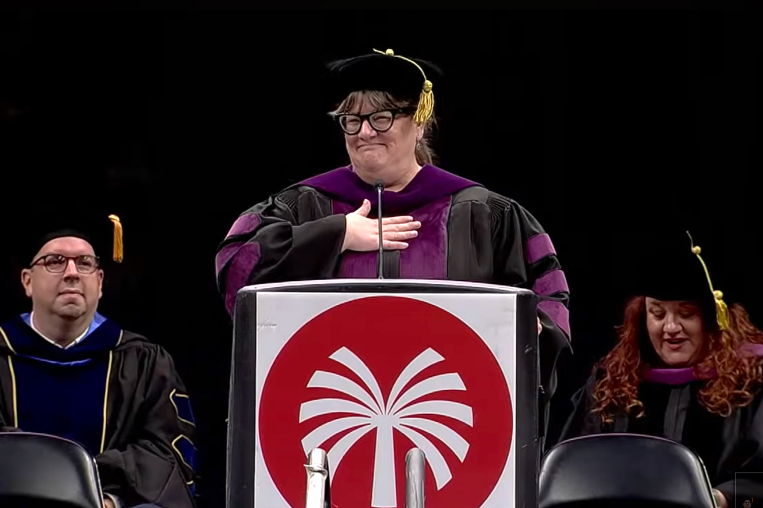Glendale Community College president Tiffany Hernandez standing a microphone during a graduation ceremony.