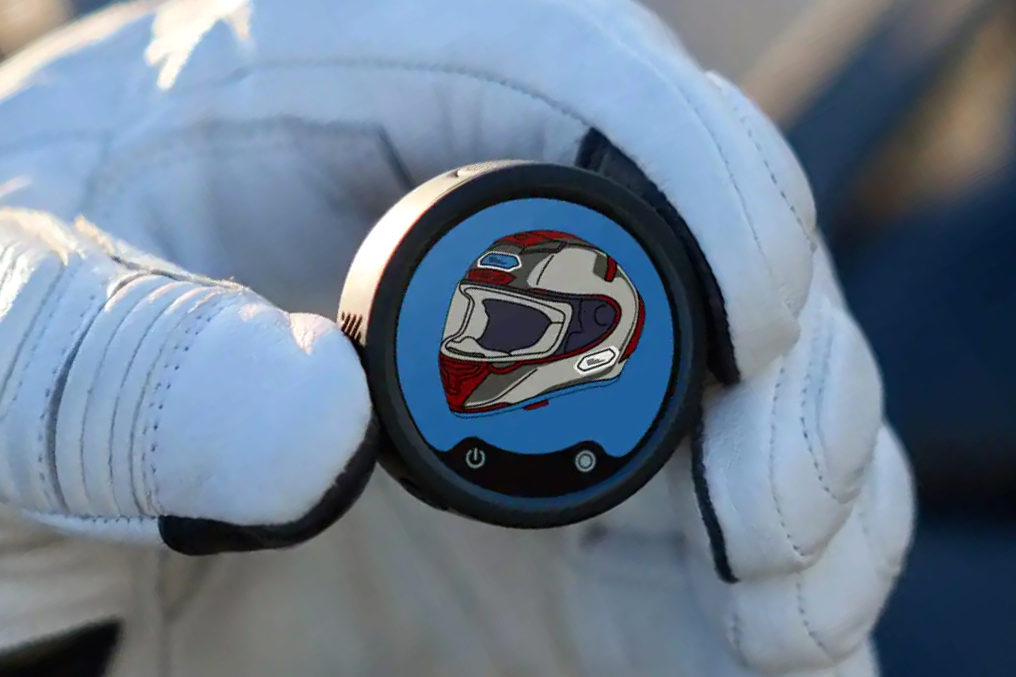 A person wearing gloves holds an Insta360 Mic Pro transmitter in their fingers showing a helmet on screen.