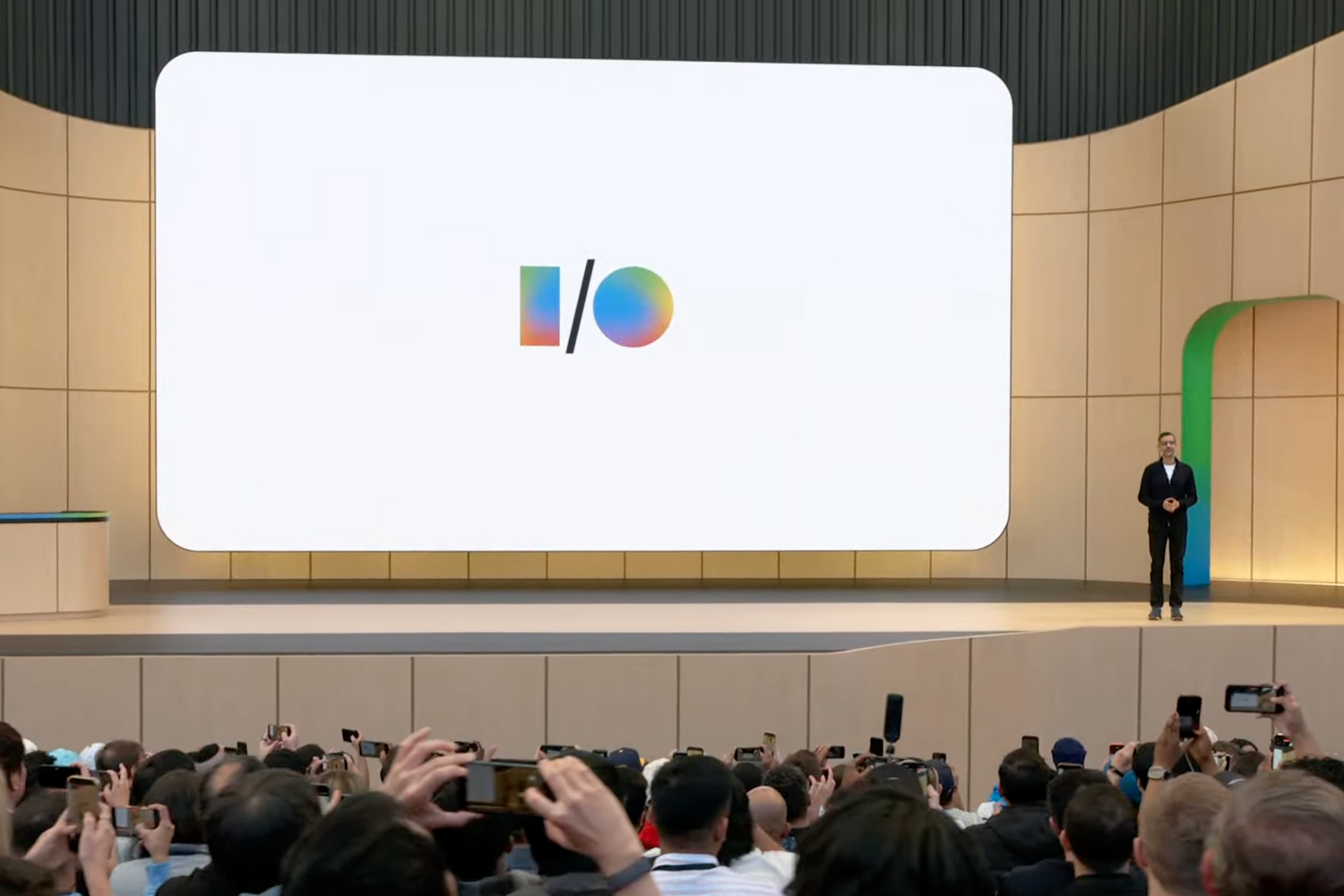 Google CEO Sundar Pichai standing on the stage at Google I/O 2026 next to a large screen showing the conference’s logo.