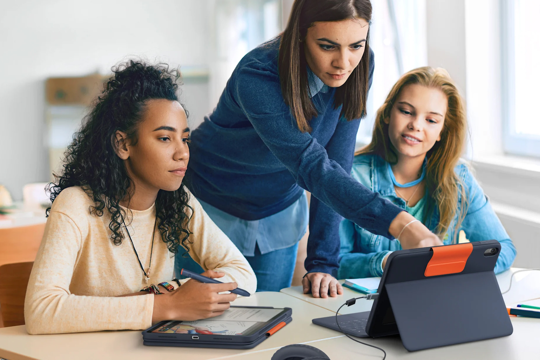 A teacher points at a screen while students work on iPads protected by Logitech’s keyboard case.