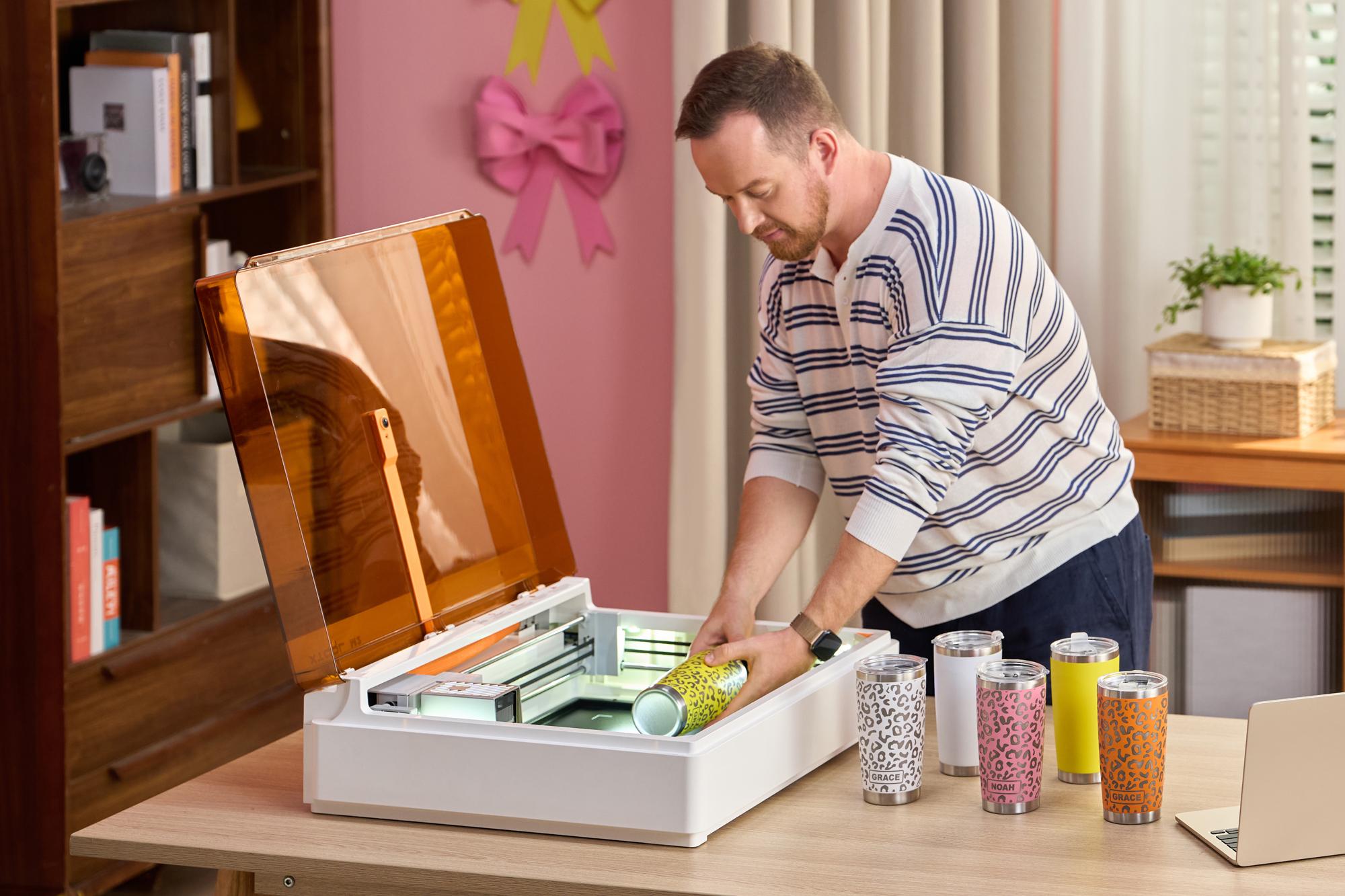A person removes an engraved water bottle from the xTool M2 crafting machine.