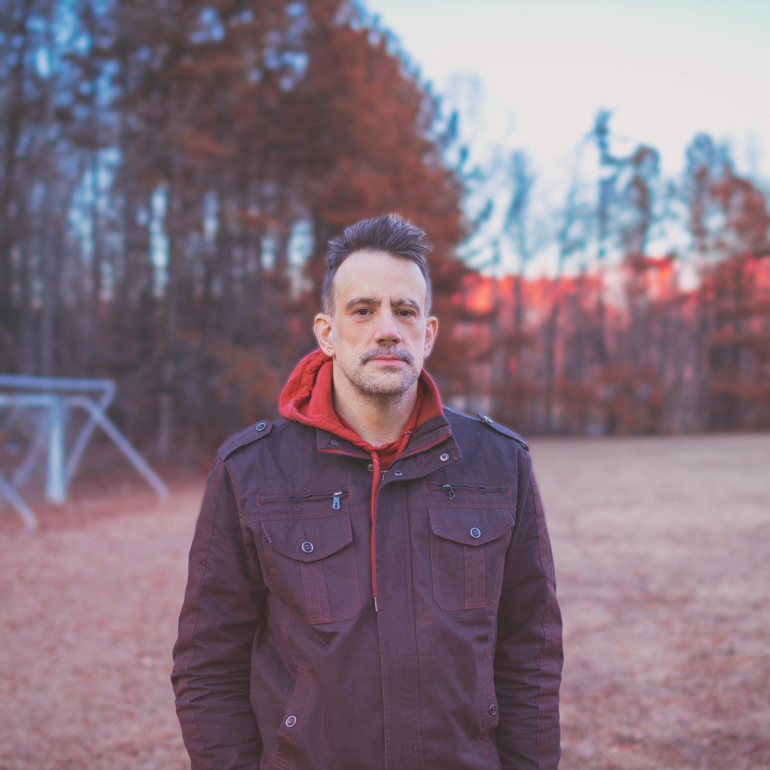 YouTuber and musician Benn Jordan in a black jacket standing in a field.