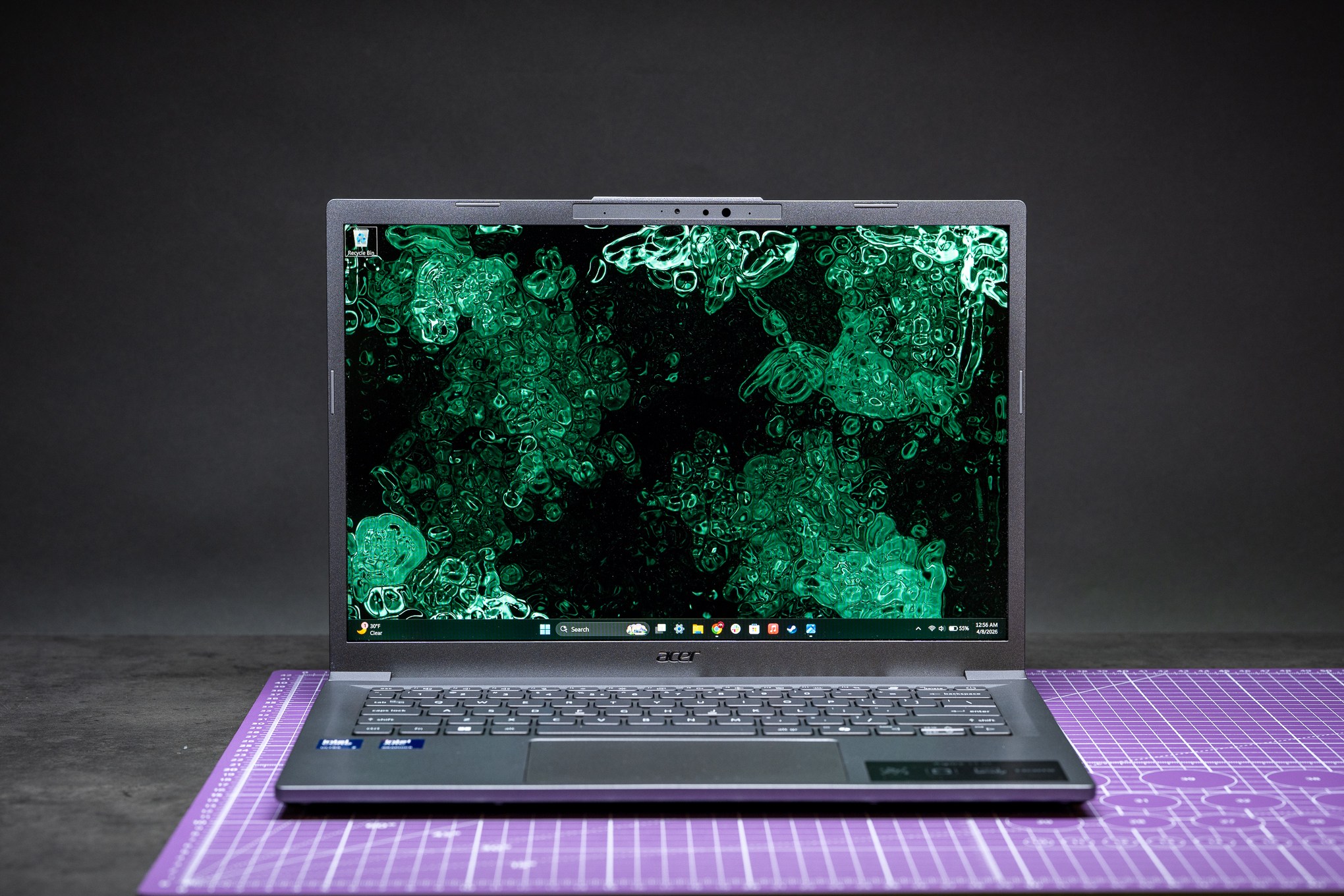 An Acer Aspire 14 laptop on a purple cut mat.