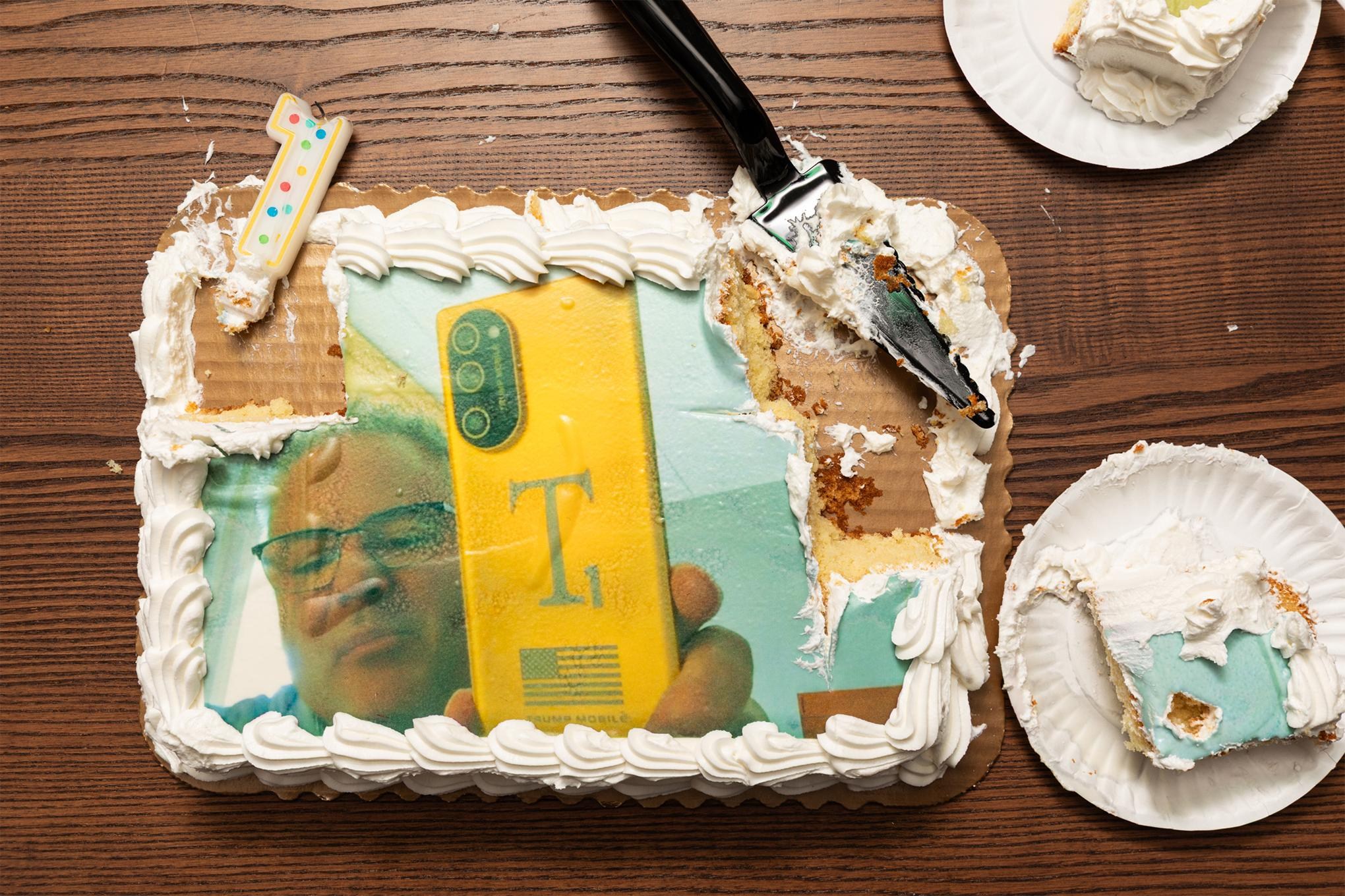 Photo of a sheet cake featuring a man holding the Trump Mobile phone.