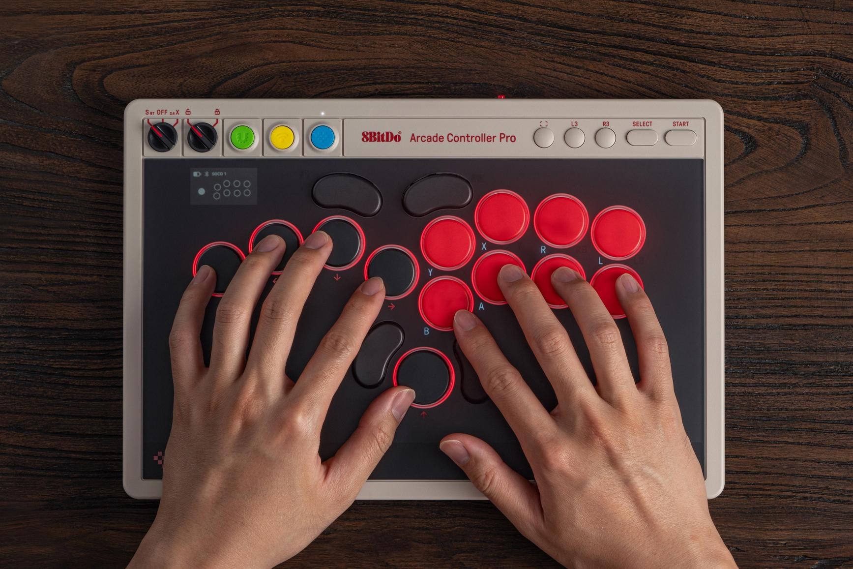 Two hands hover over several buttons on the 8BitDo Arcade Controller Pro.