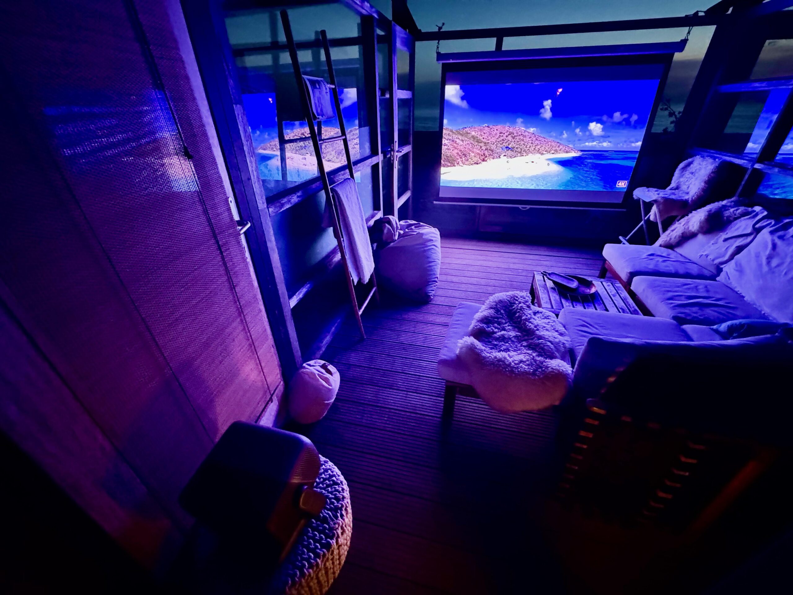 The N3 Ultimate projects an idyllic kitesurfing scene on a pull-down screen hung from an outdoor terrace at night.
