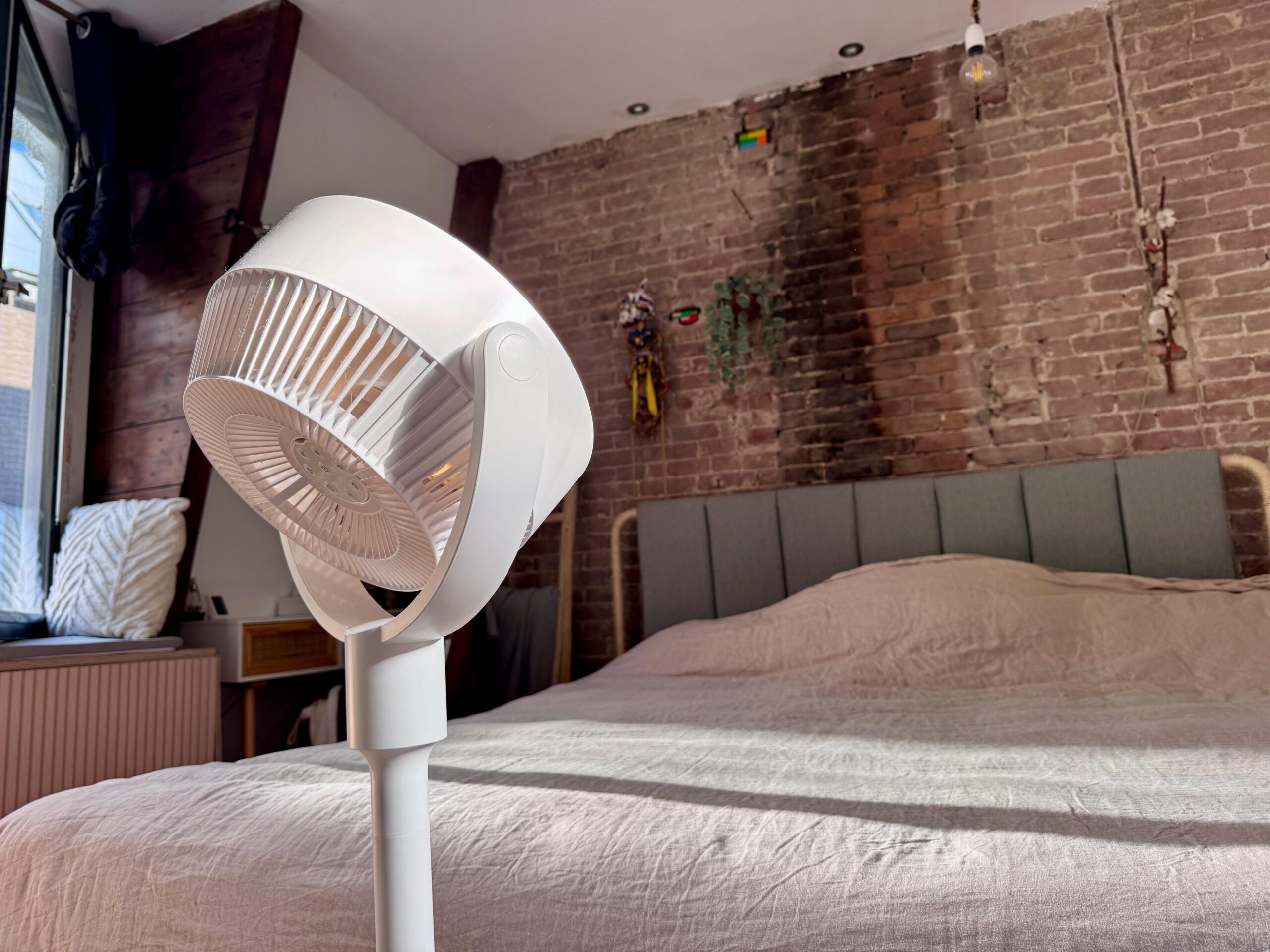 A SwitchBot Standing Circulator Fan pointing at a brick wall.