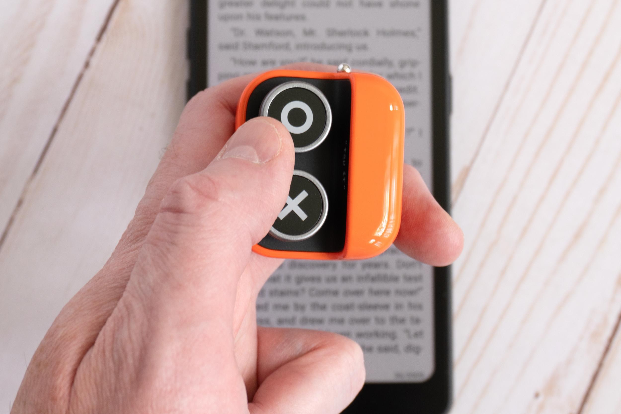 A person holding and pressing a button on the Boox Tappy with an e-reader in the background. A person holding and pressing a button on the Boox Tappy with an e-reader in the background.