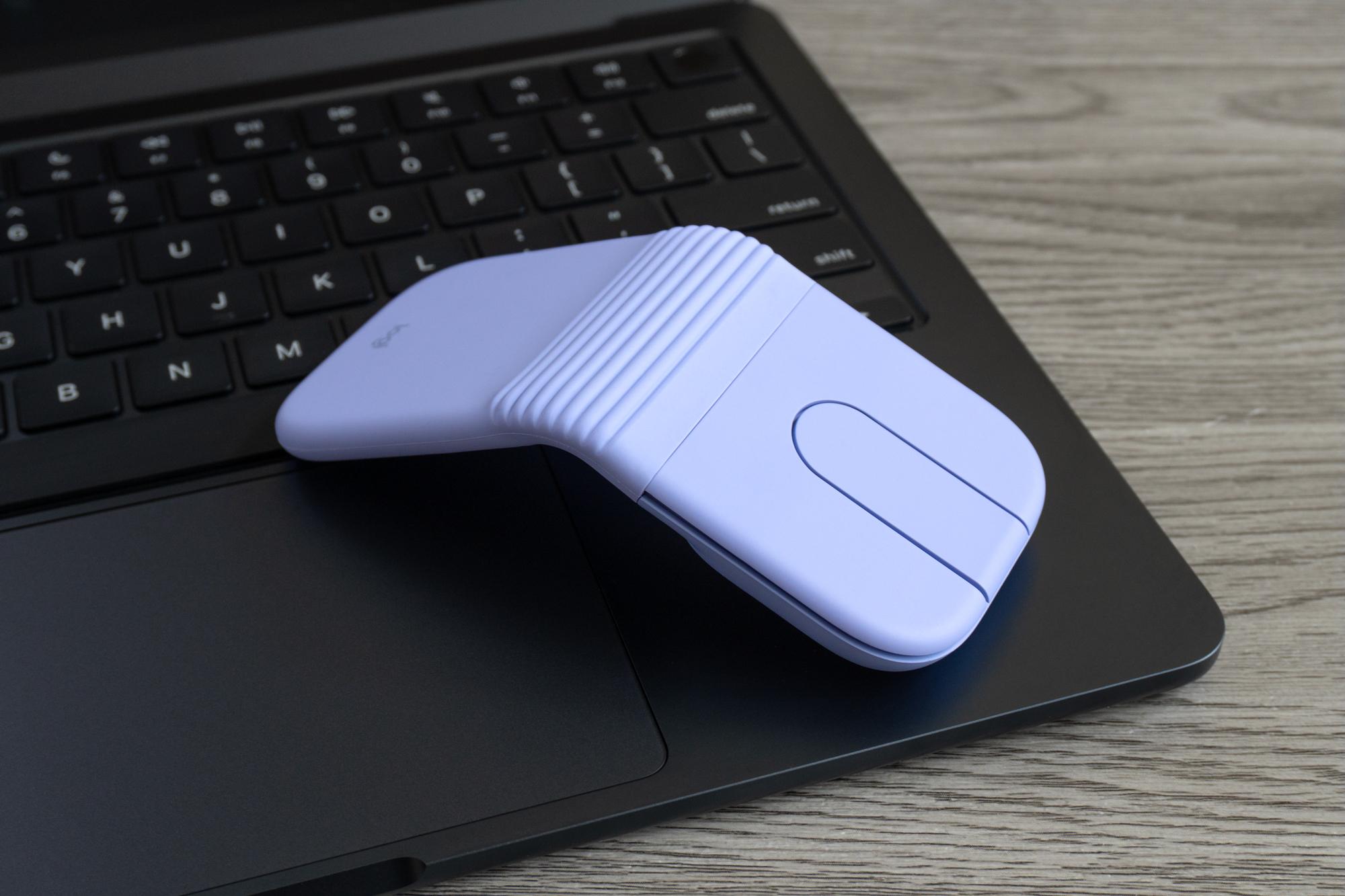 The Logitech Mobi Fold mouse open and sitting on the corner of an Apple laptop.