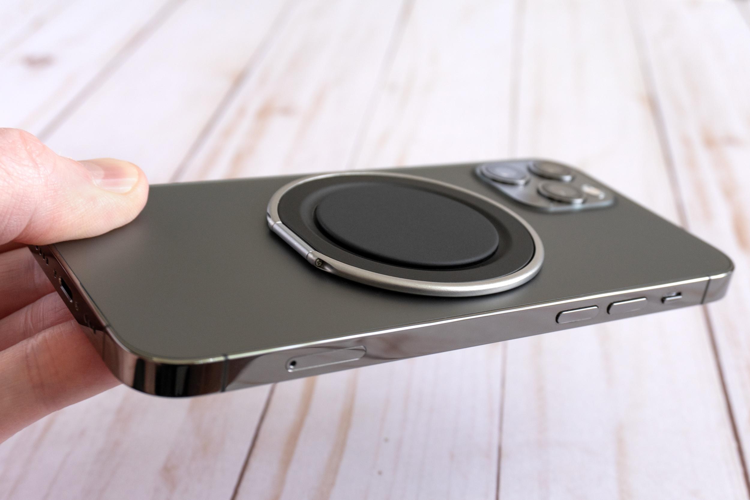 A person holds an iPhone 12 Pro smartphone with a PopSockets Low-Pro Grip attached to the back.