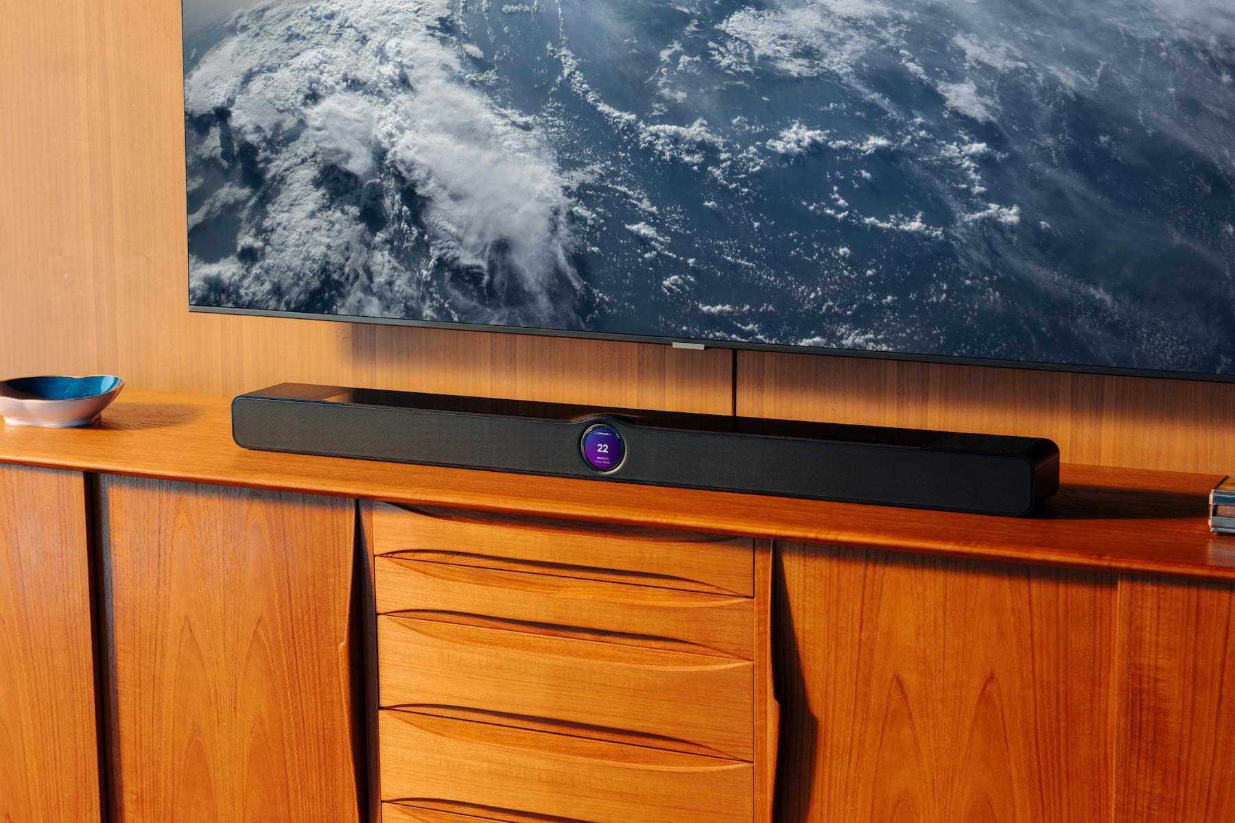 The WiiM Bar on a wooden credenza below a TV depicting an image from space.