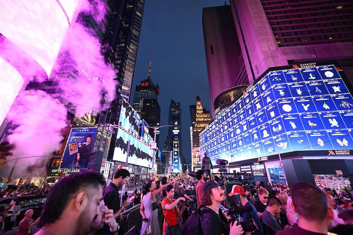 A photo of a group of people clustered into Times Square playing Pokémon Go.