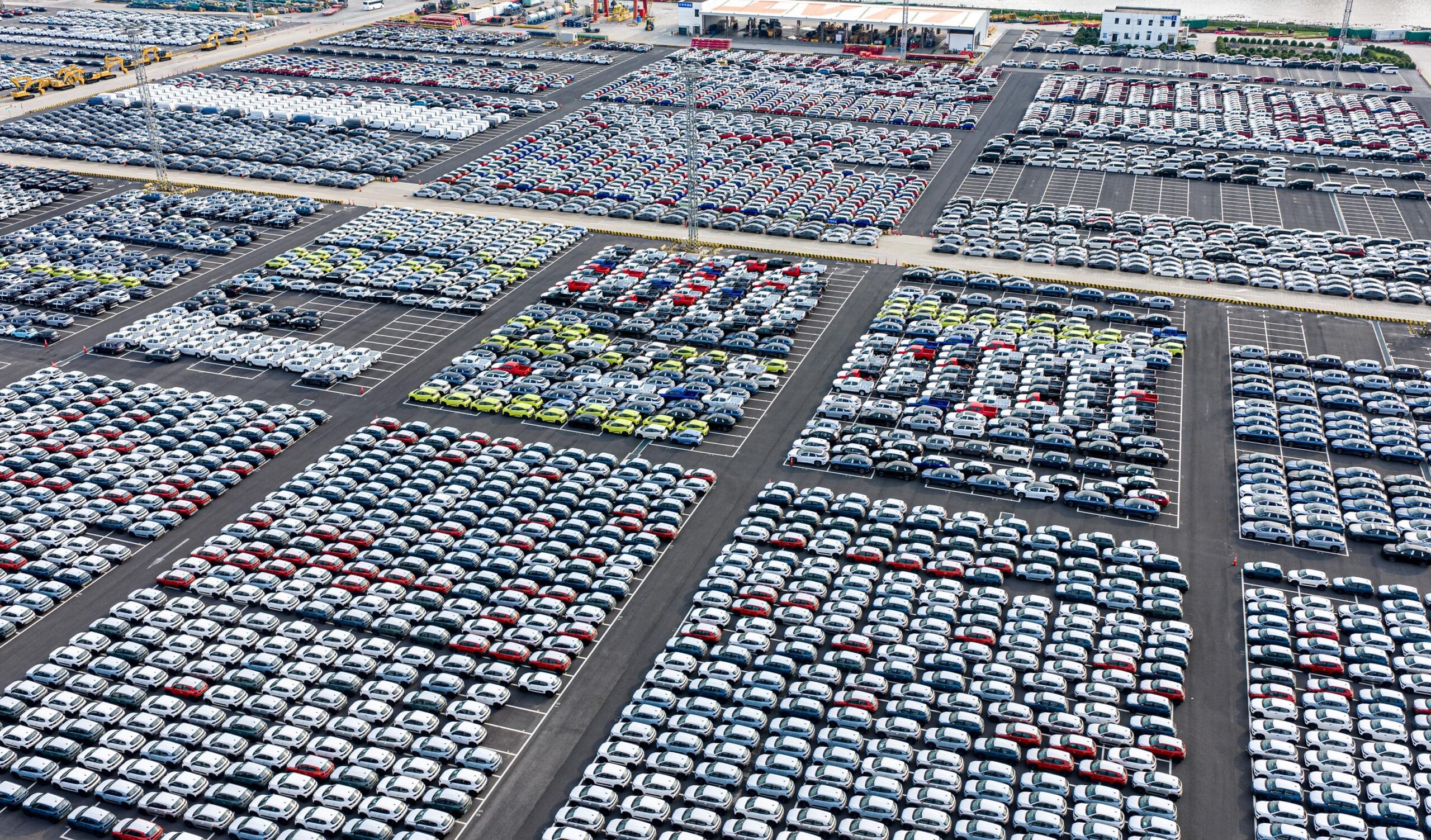 Hundreds of cars neatly arranged can be seen in an enormous parking lot from above. Hundreds of cars neatly arranged can be seen in an enormous parking lot from above.