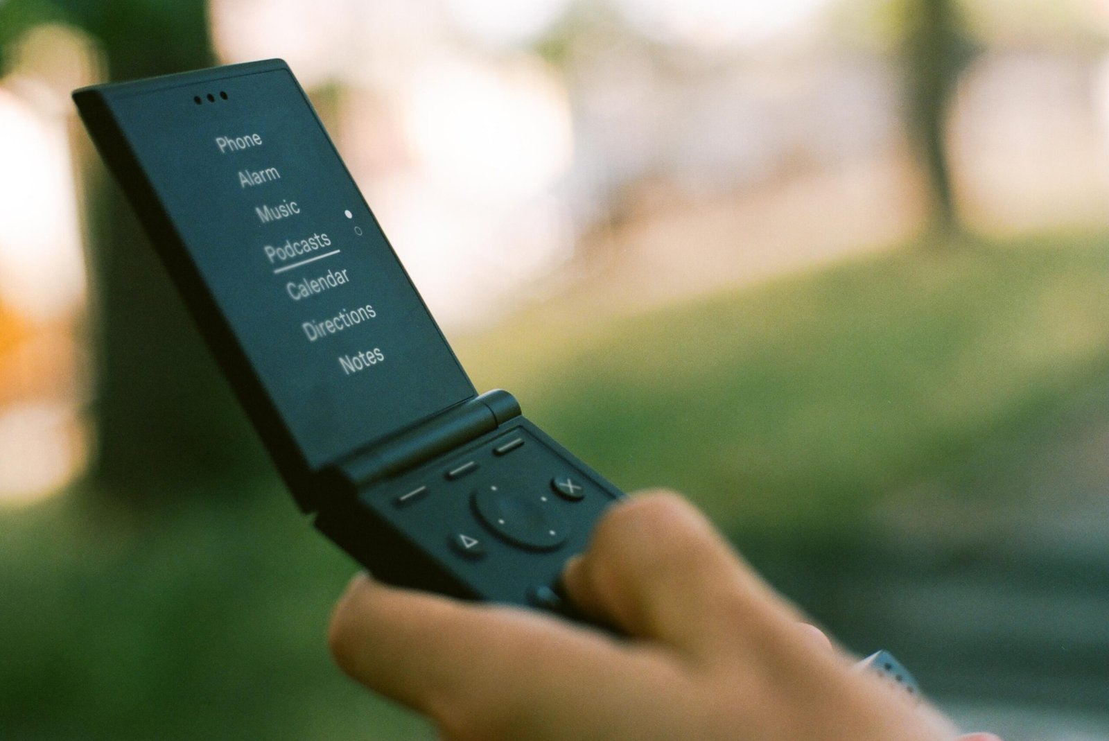 A person’s hand holding a large black flip phone.