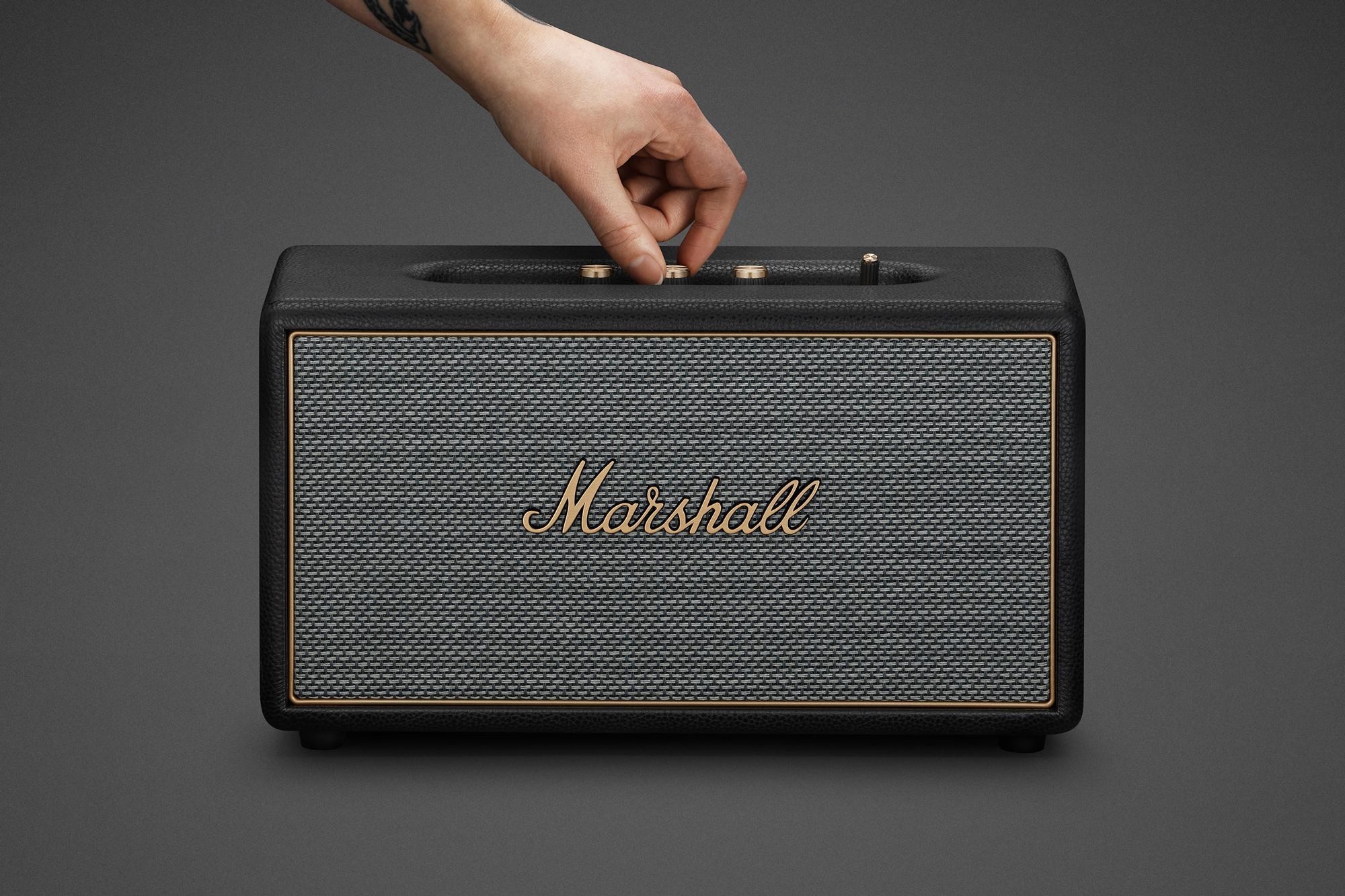 A person adjusts a knob on top of the Marshall Stanmore IV wireless speaker.