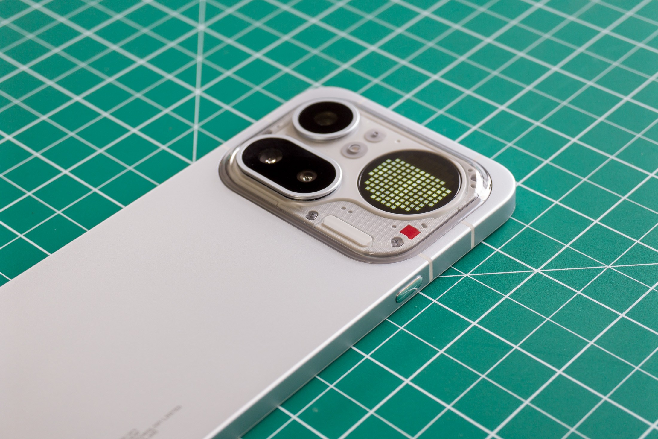 Photo of Nothing Phone 4A Pro on a green cutting mat showing the camera module with a battery level indicator on the Glyph Matrix