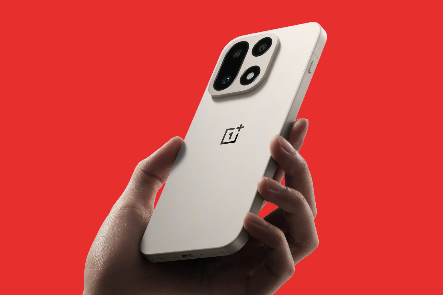 A hand holding a OnePlus 15 in Sand Storm color in front of a red background