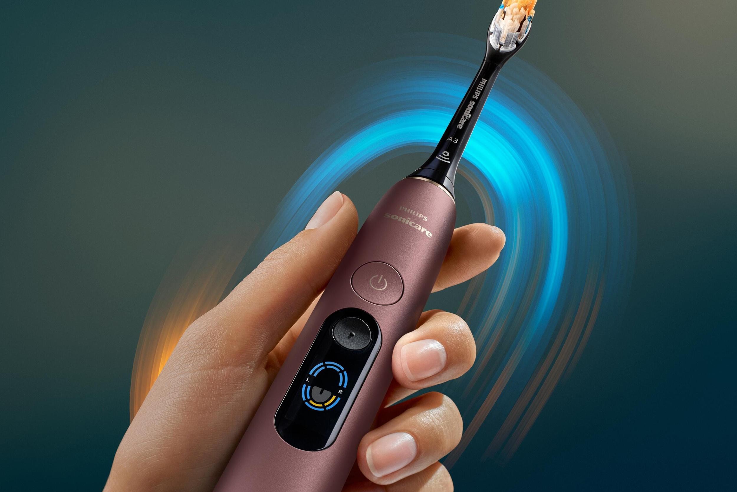 A person holds the Philips Sonicare Next-Generation DiamondClean 9900 Prestige smart toothbrush with a glowing aura around it.