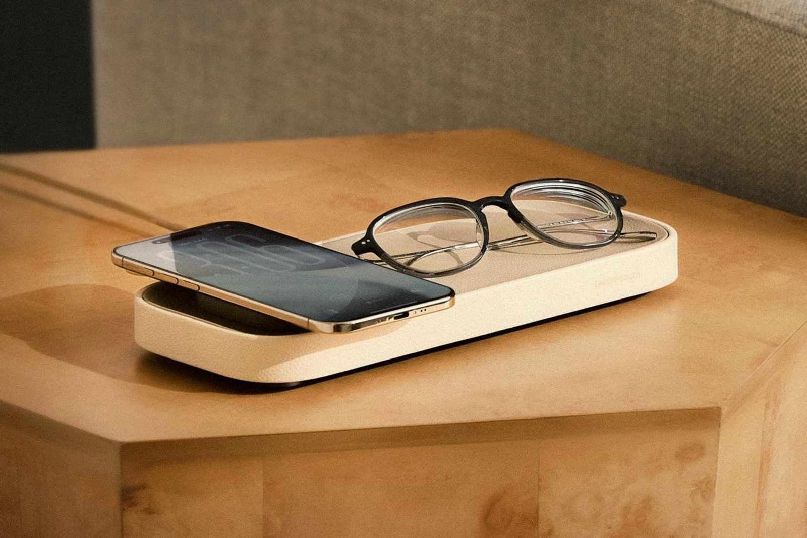 A smartphone and pair of glasses sitting on Twelve South’s Valet charging tray.