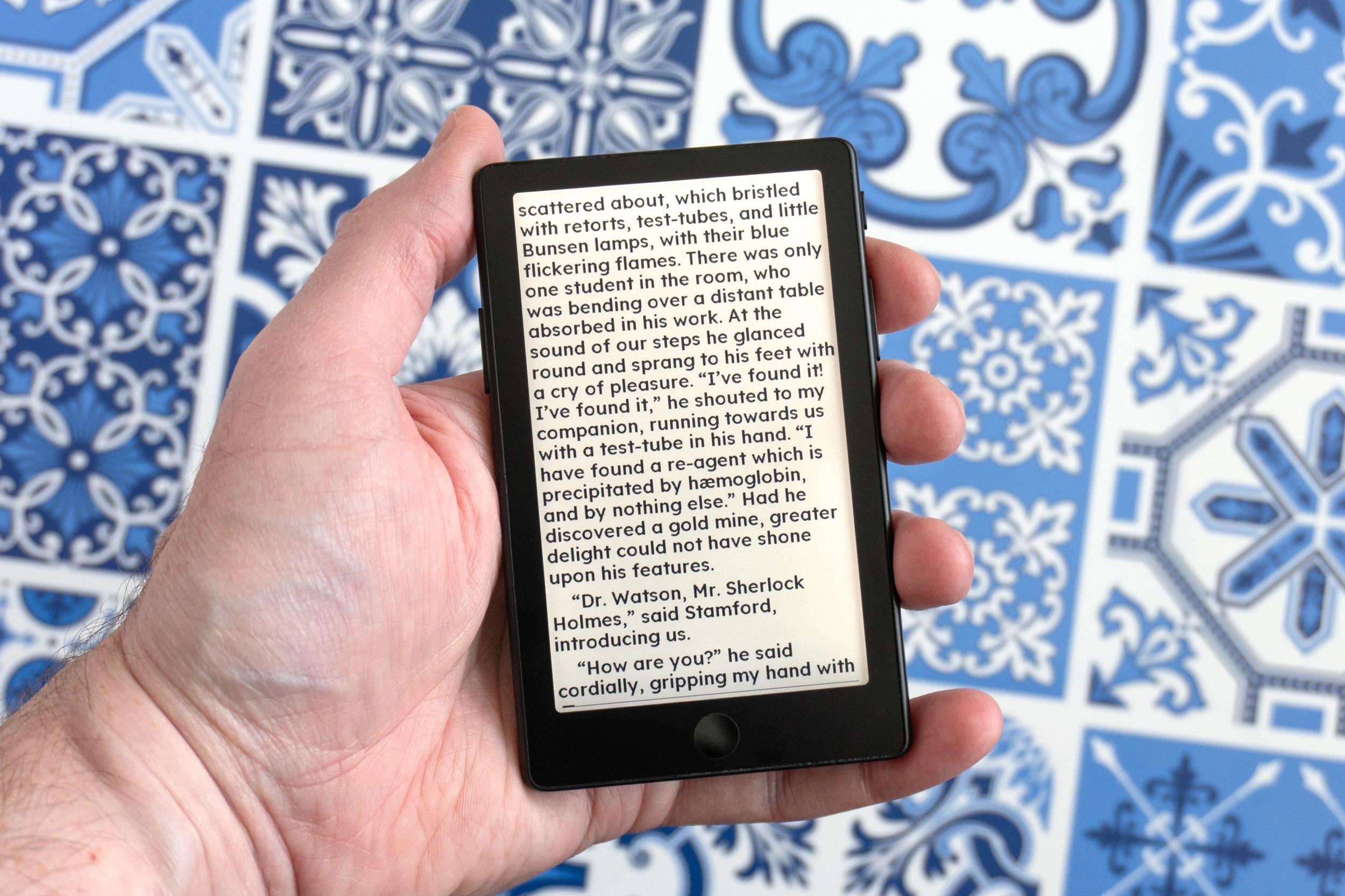 A person holding the Xteink X4 Pro e-reader with an ebook’s text displayed on screen.