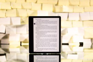 The Kindle Paperwhite standing upright in front of a background of yellow post-it notes.
