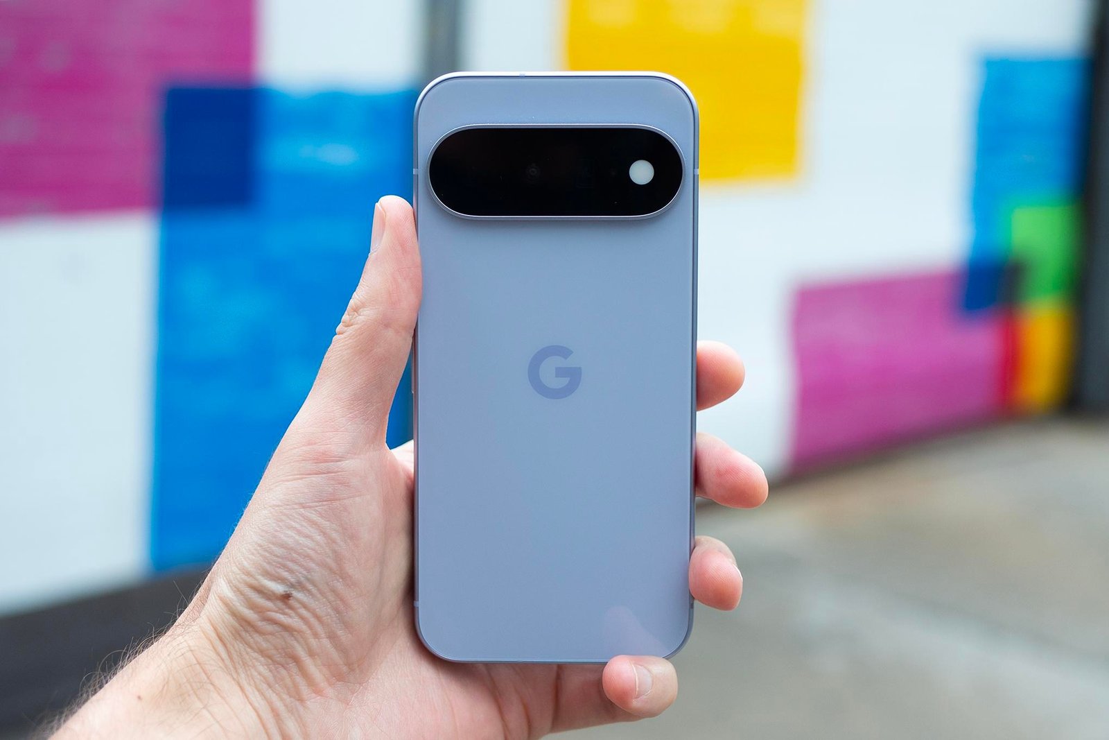 Google Pixel 11 in front of brightly colored blurry background.